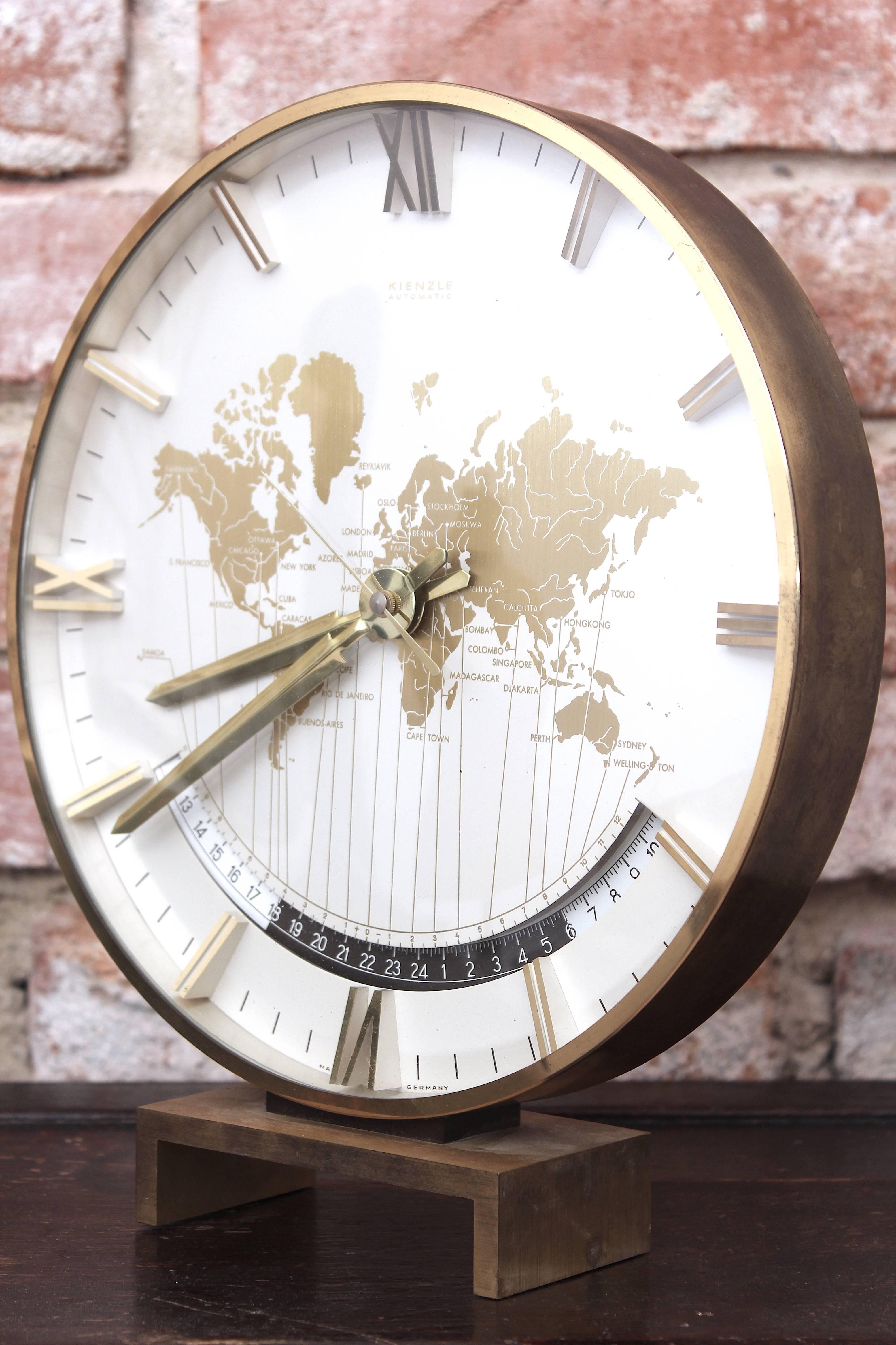This automatic World Time Zones Table Clock was manufactured by Kienzle (Kienzle Uhren GmbH is Germany's oldest watchmakers, founded in 1822 in Schwenningen ) and features a crystal glass cover with solid brass elements. The clock measures 26 cm in