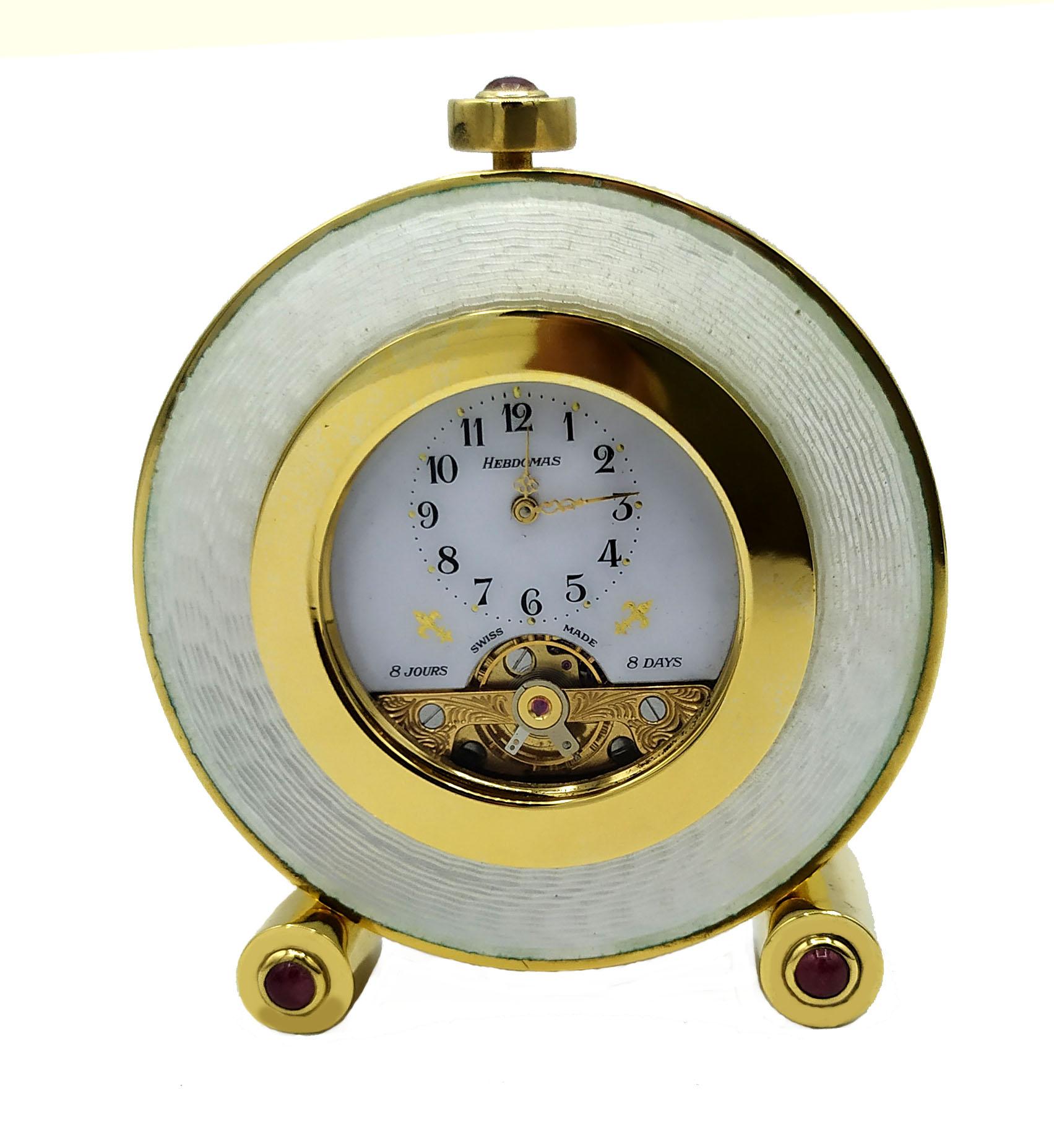 Small round table clock with cylindrical feet in 925/1000 sterling silver gold plated with translucent fired enamel on guillochè with 3 cabochon pink tourmalines diameter mm. 4. “Hebdomas” Swiss mechanical movement with visible balance wheel and