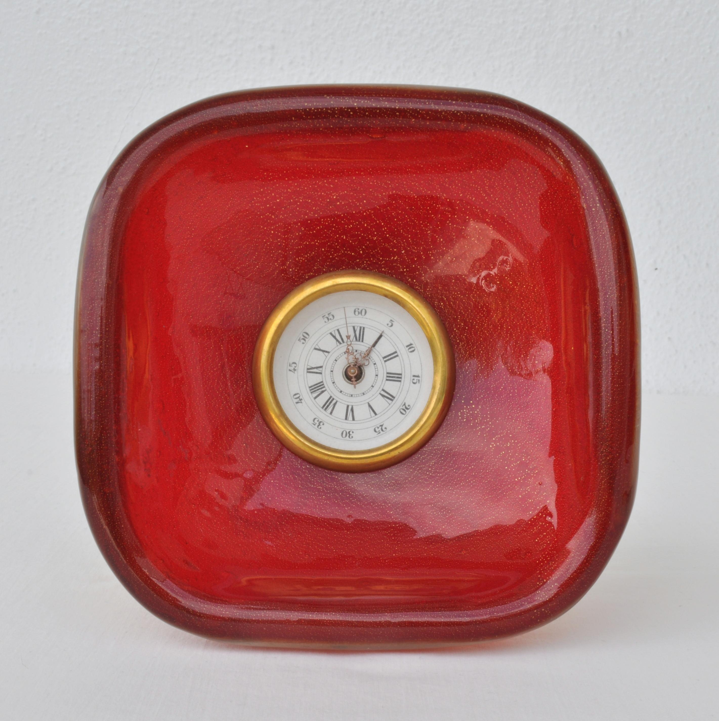 Layers of gold flake and red. The concave, square in form has rounded corners. The clock with original wind up clock inserted
On a brass stand. The position makes the color rich because the light goes through it.

Square concave Somerso table