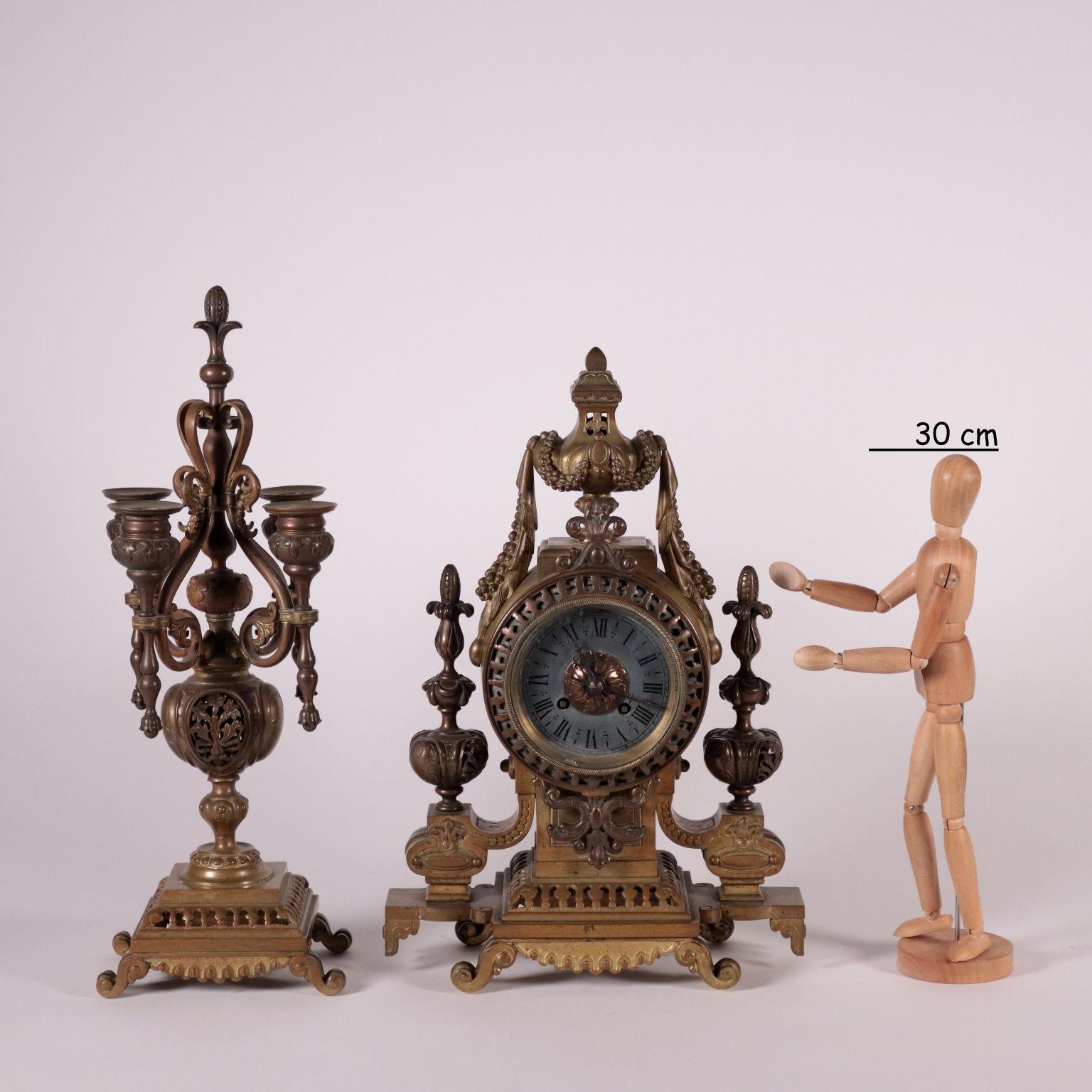 Table clock with bronze candlesticks. Pierced decorations, plant patterns, garlands and festoons. Metal vise with roman numbers for hours and iron hands. Branded Japy Freres medaille d'honneur & C.ie. The candlesticks have 4 flames and are 43 cm