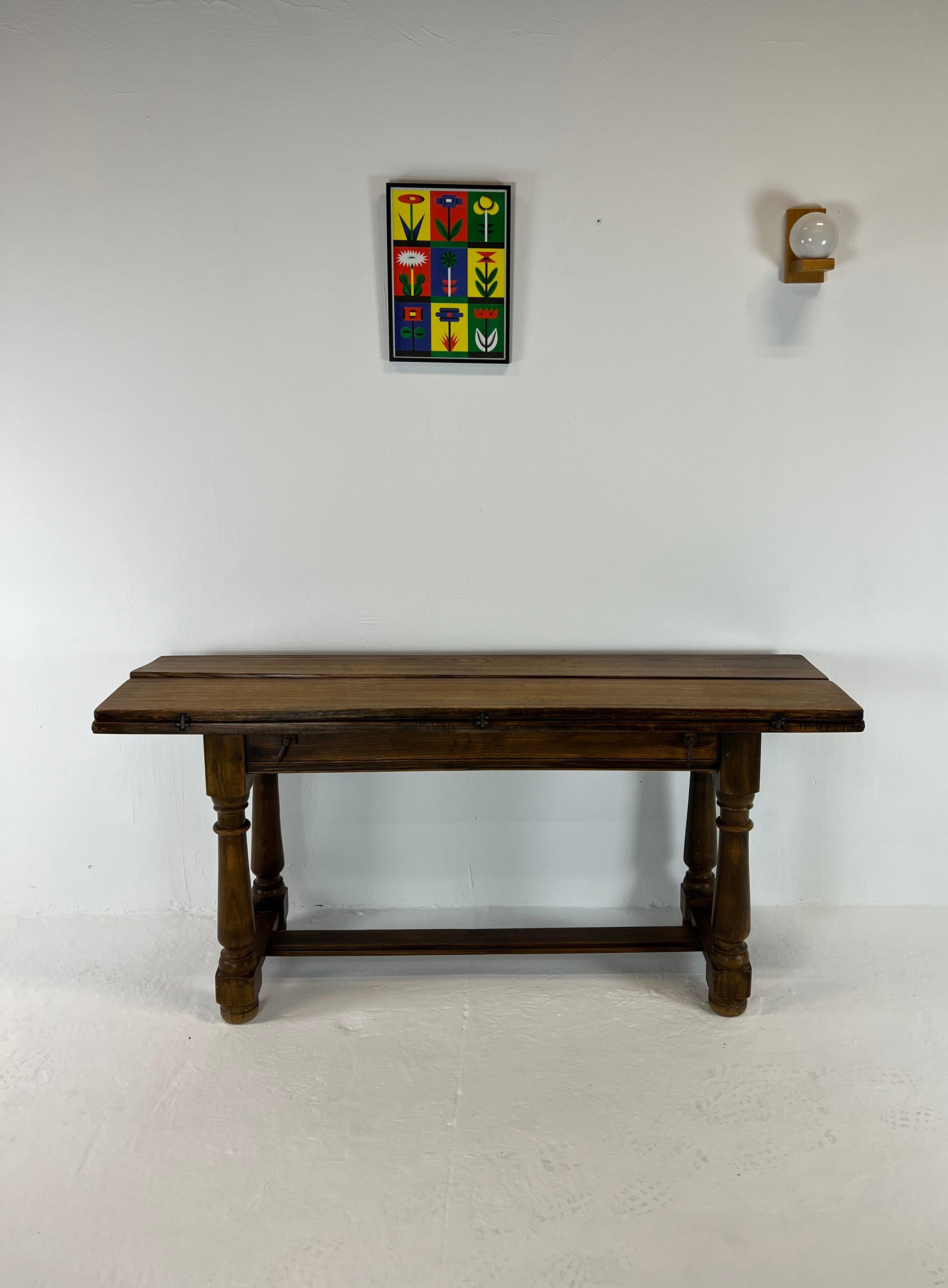 Very pretty dining table - console in oak with turned legs, from the 1900s. It has two horizontal extensions held by superb wrought iron hinges. The extensions rest on two pull tabs that come out on each side. The zippers are decorated at their ends