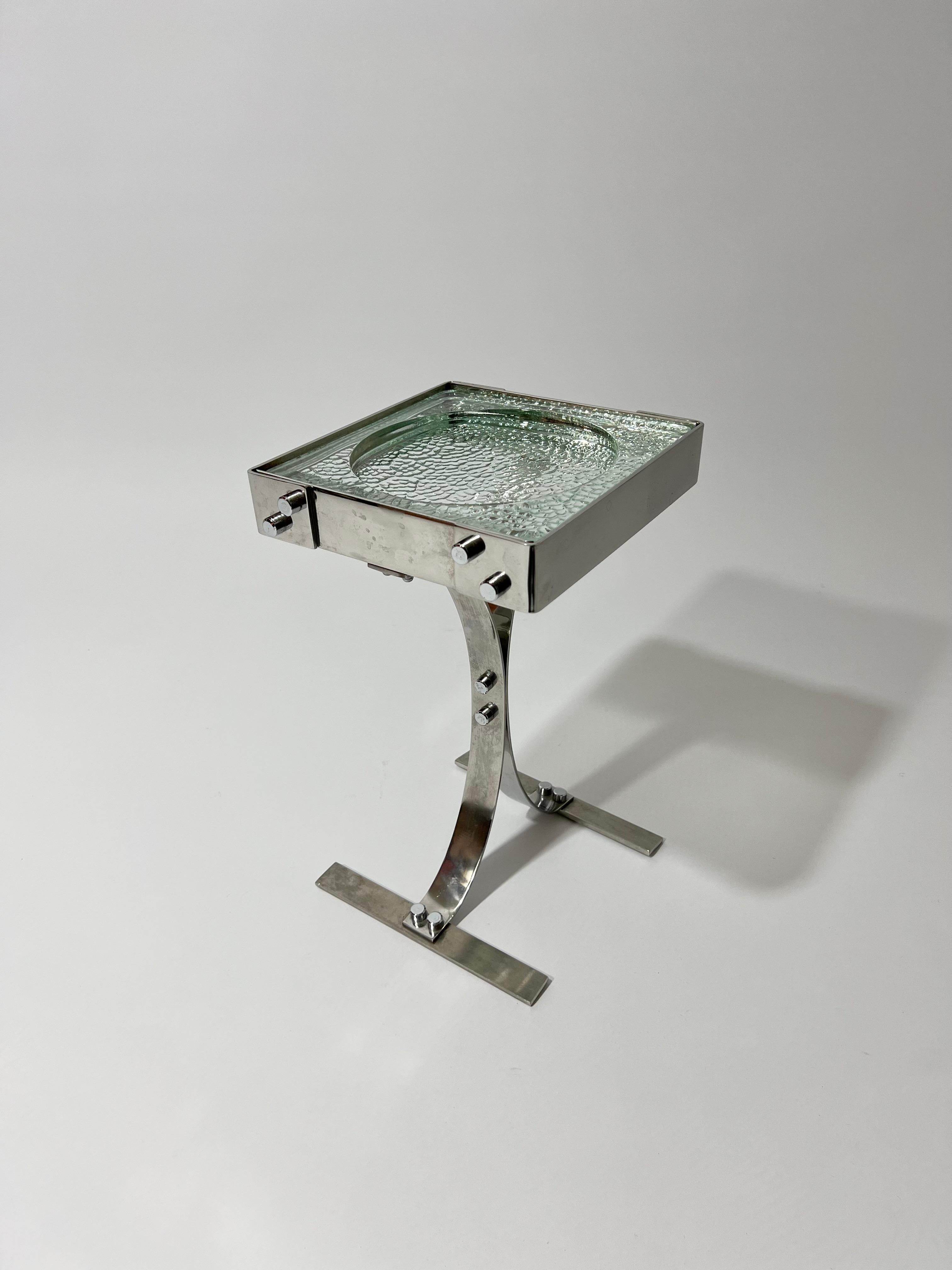 Table d'appoint vide poche ou encore cendrier en inox et pavé de verre Nevada, France, années 1970. Création non attribué, travail dans le goût de Jacques Adnet, Joelle Ferlande ou encore Francois Monnet. Le pavé de verre Nevada à été régulièrement
