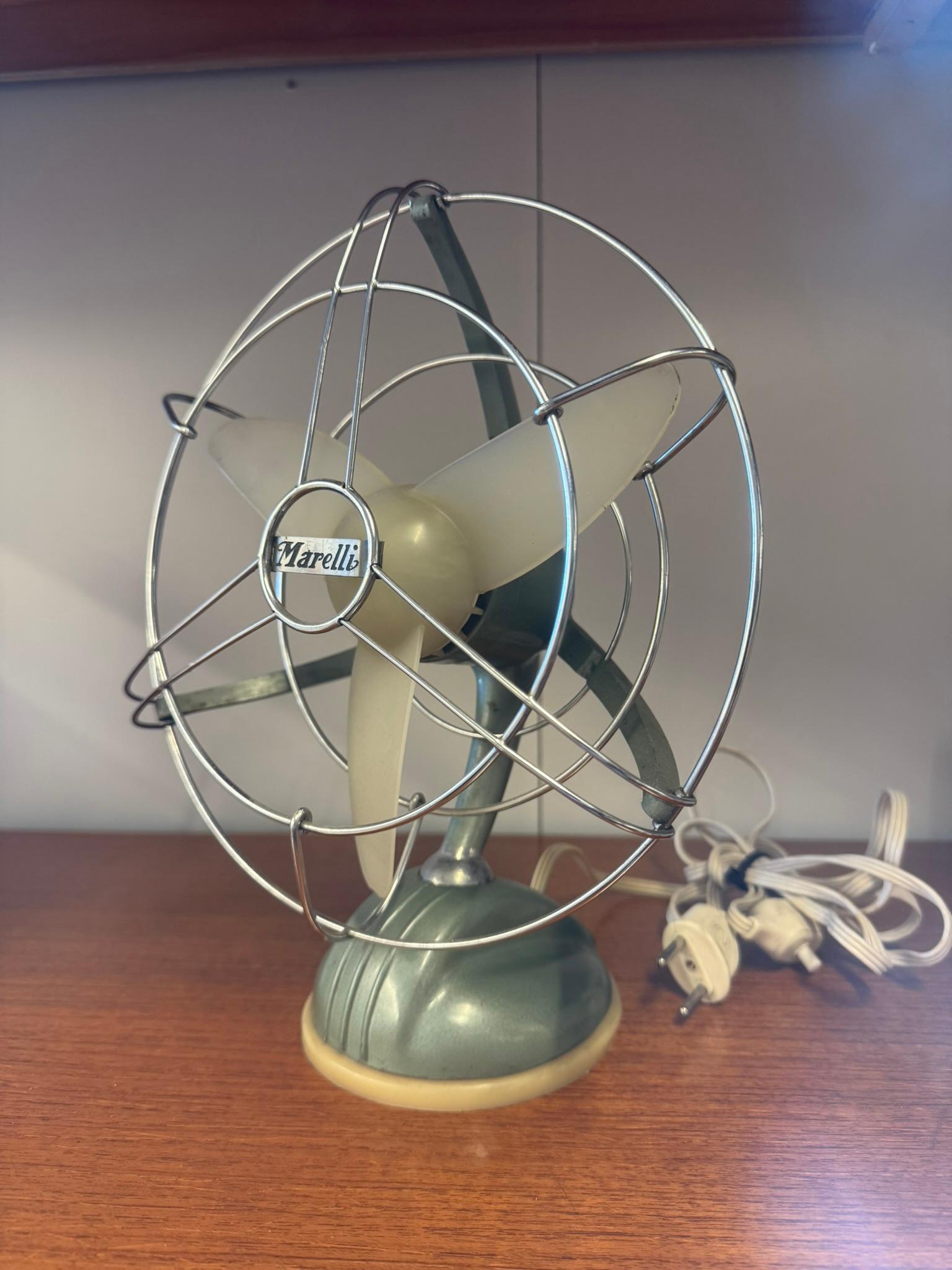 Raro e da collezione ventilatore da tavolo Marelli, modello I 202, risalente al 1953. Questa versione è dotata di una sola velocità, rotazione e inclinazione manuale e può essere utilizzata sia come ventilatore da appoggio che da sospensione. 

Il