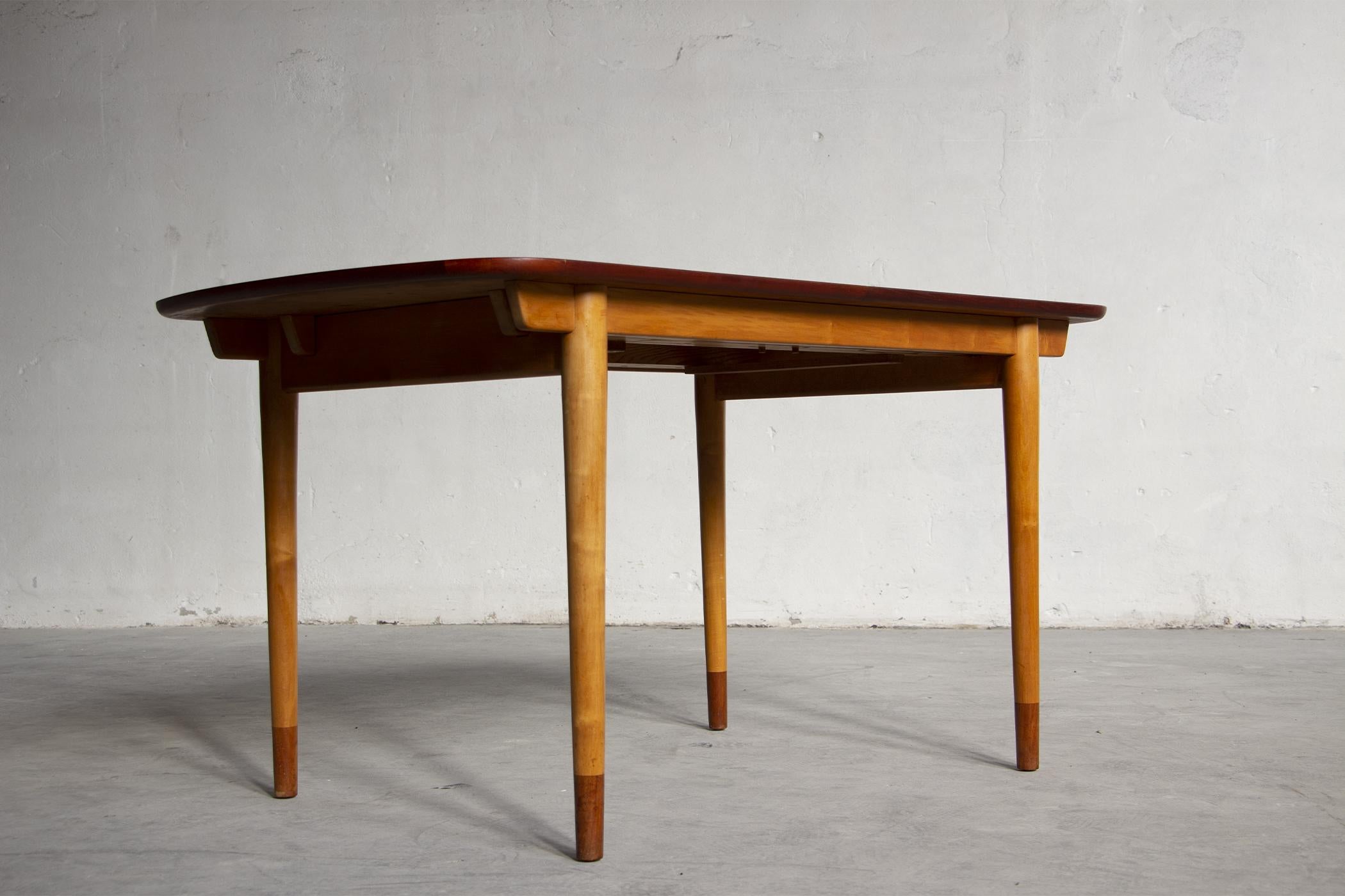 Rare and exceptional Finn Juhl dining table with rectangular teak veneer top with two maple veneer extensions that can be stored under the central top. The structure is in solid maple, tapered legs with solid teak tips. Designed in 1949. Produced by