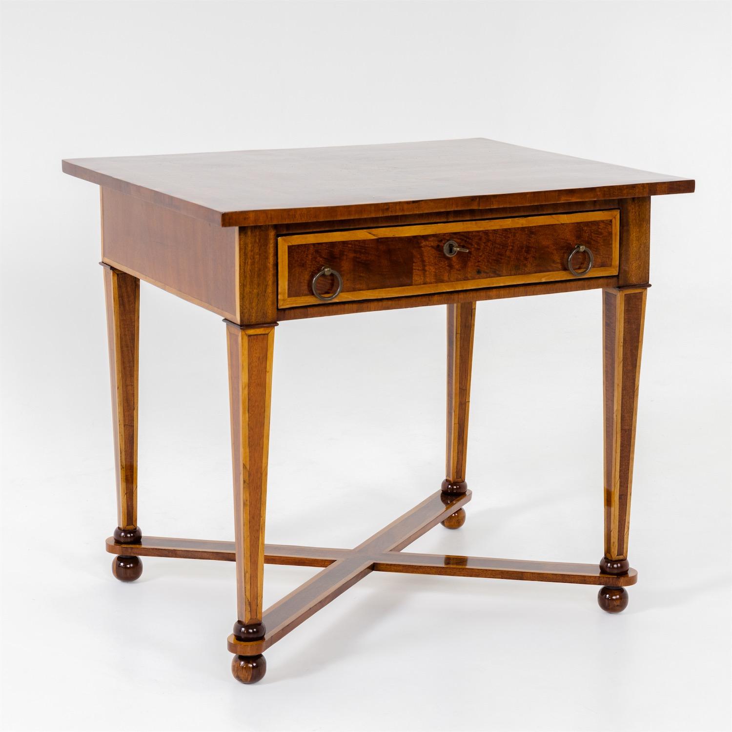 Table with wide drawer and ring-shaped pull handles. The tapered legs rest on ball feet with x-shaped bracing. The tabletop with beautiful inlays.