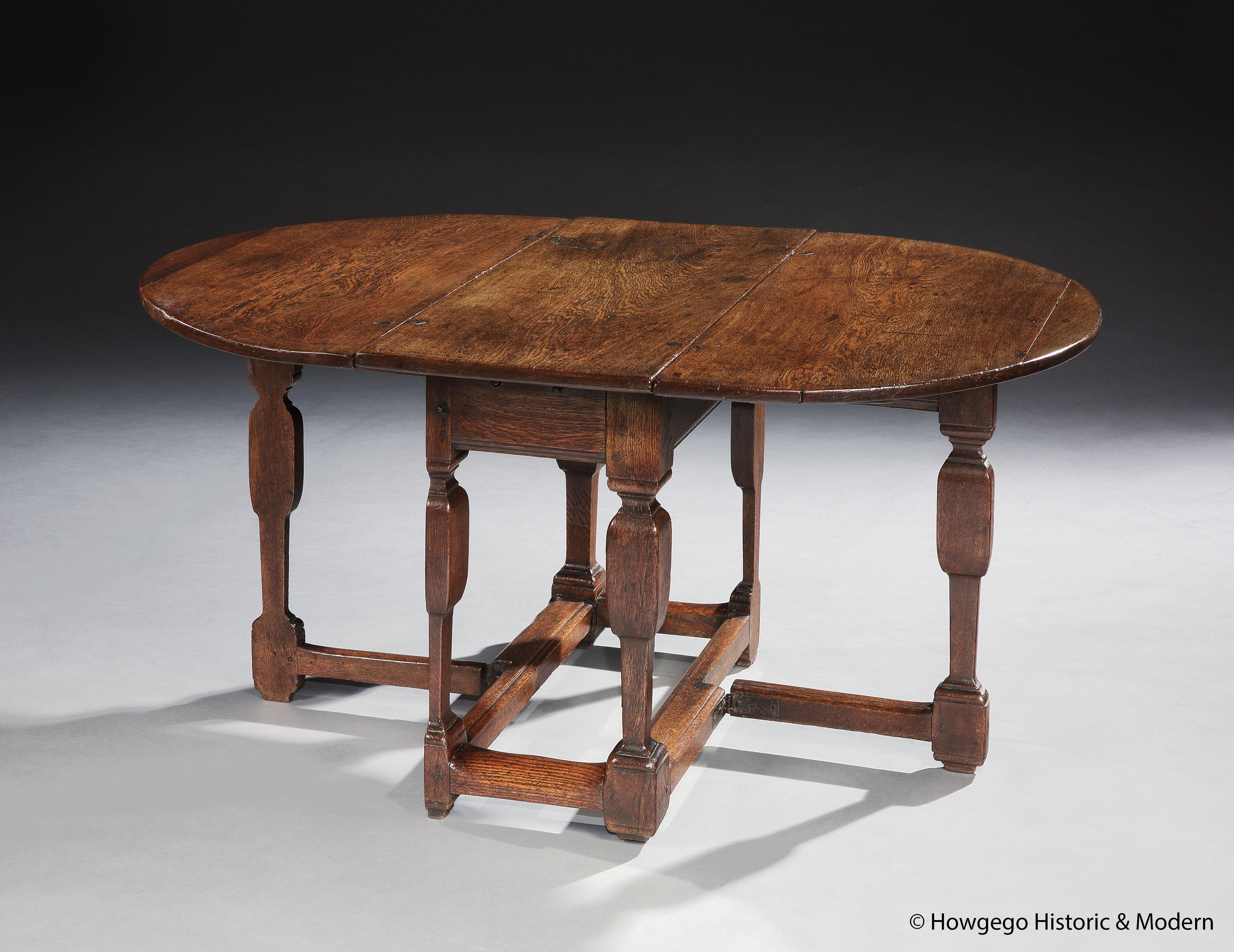 Une table ovale en chêne, fendue, en forme de porte, avec un travail de ferronnerie original et un tiroir unique, 5 pieds, de style baroque.

- Les tournures sont d'inspiration architecturale et le pied fendu crée une silhouette épurée et élégante
-