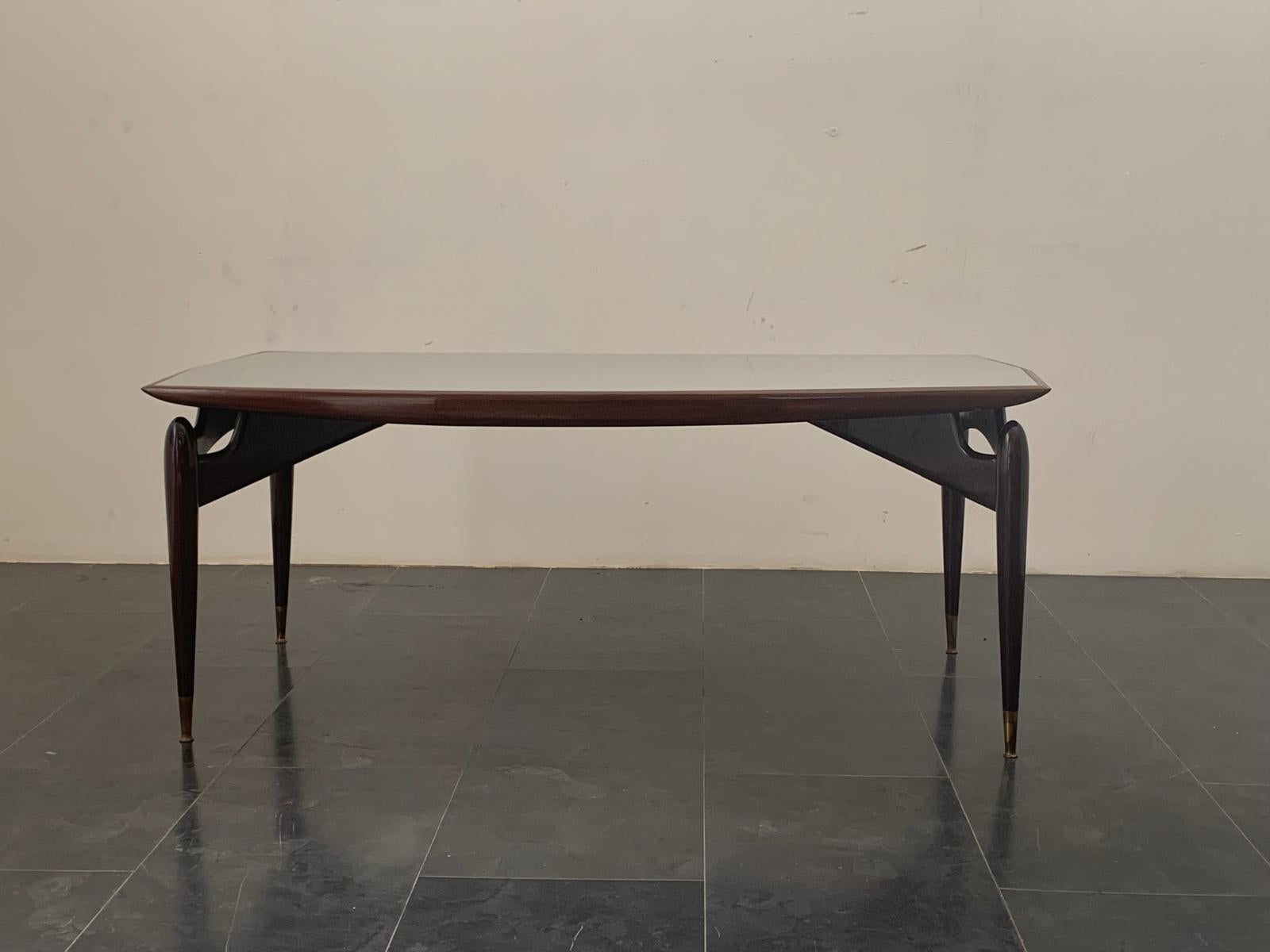Table en acajou et palissandre avec plateau en verre, années 1950. Exécuté de main de maître dans une combinaison exquise de bois de rose et d'acajou, toutes les lignes de l'armoire sont courbes et arrondies. Quatre pieds en acajou partent de