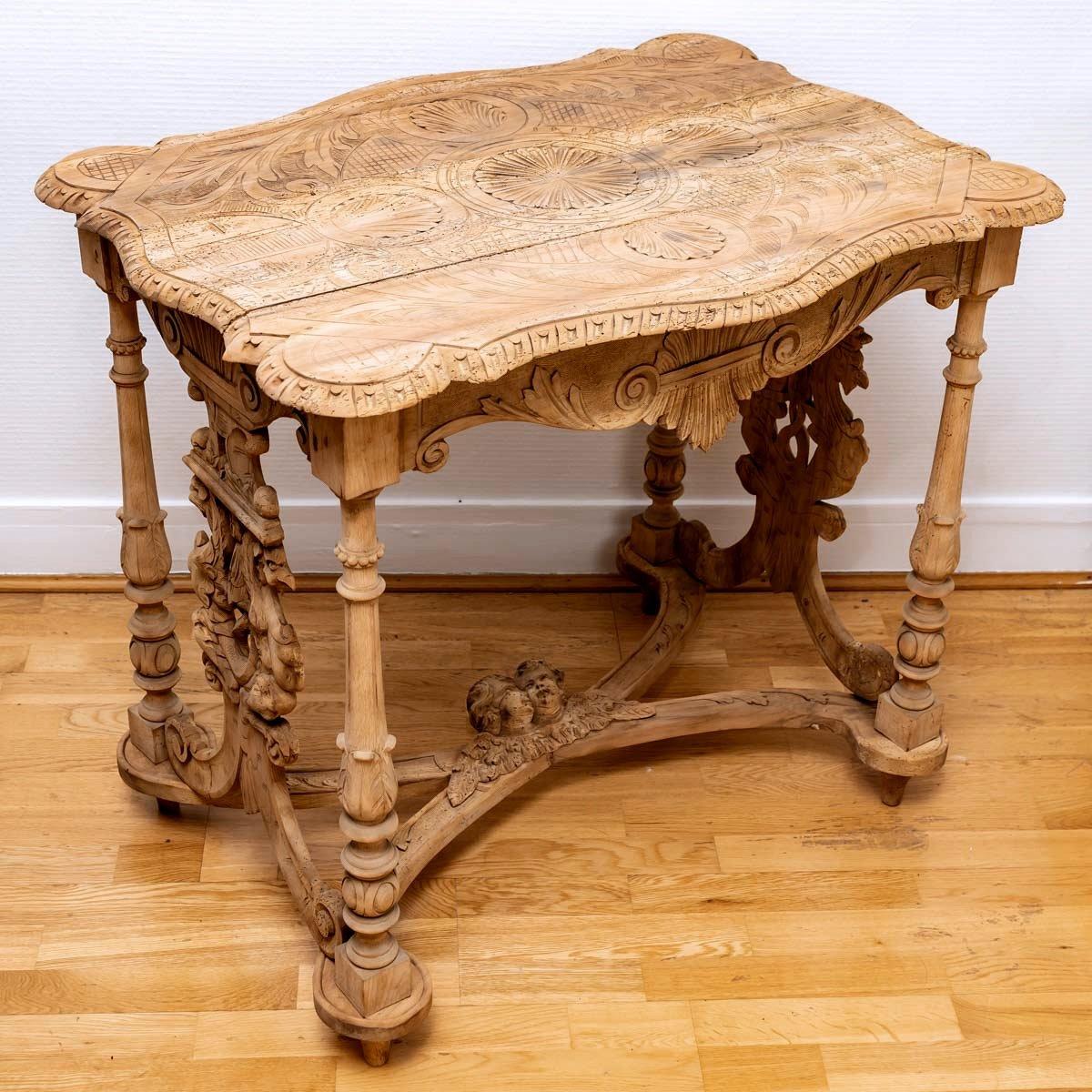 Small coffee table in solid walnut.  
It rests on four turned and carved legs connected by an X-shaped spacer also carved with acanthus leaves and winged putti.
 
This very beautiful piece of furniture, a unique part of a complete living room, was