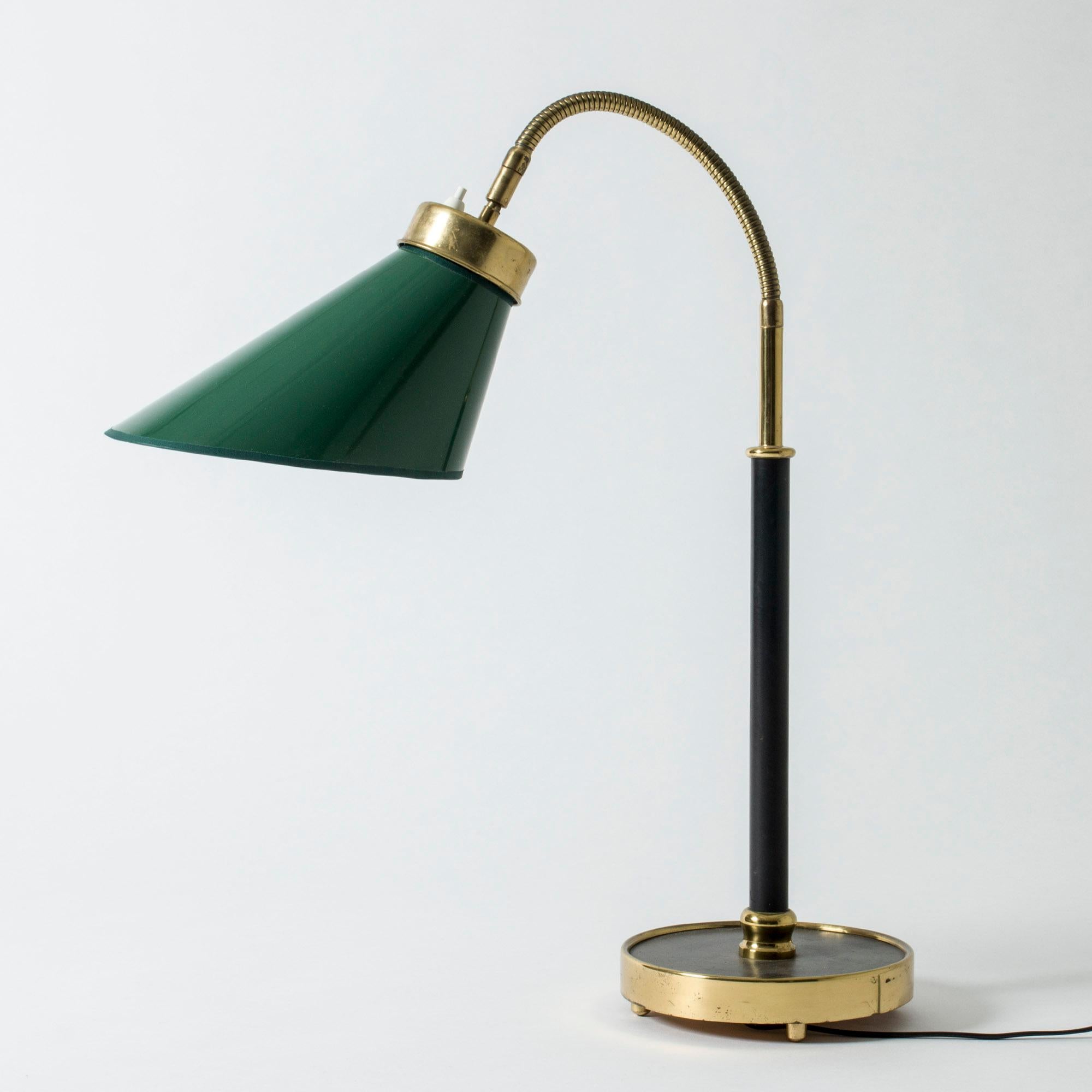 Very rare, elegant brass table or desk lamp by Josef Frank, with a dark green shade. Original black leather upholstery on the stem and base. Flexible neck and decorative round brass feet.