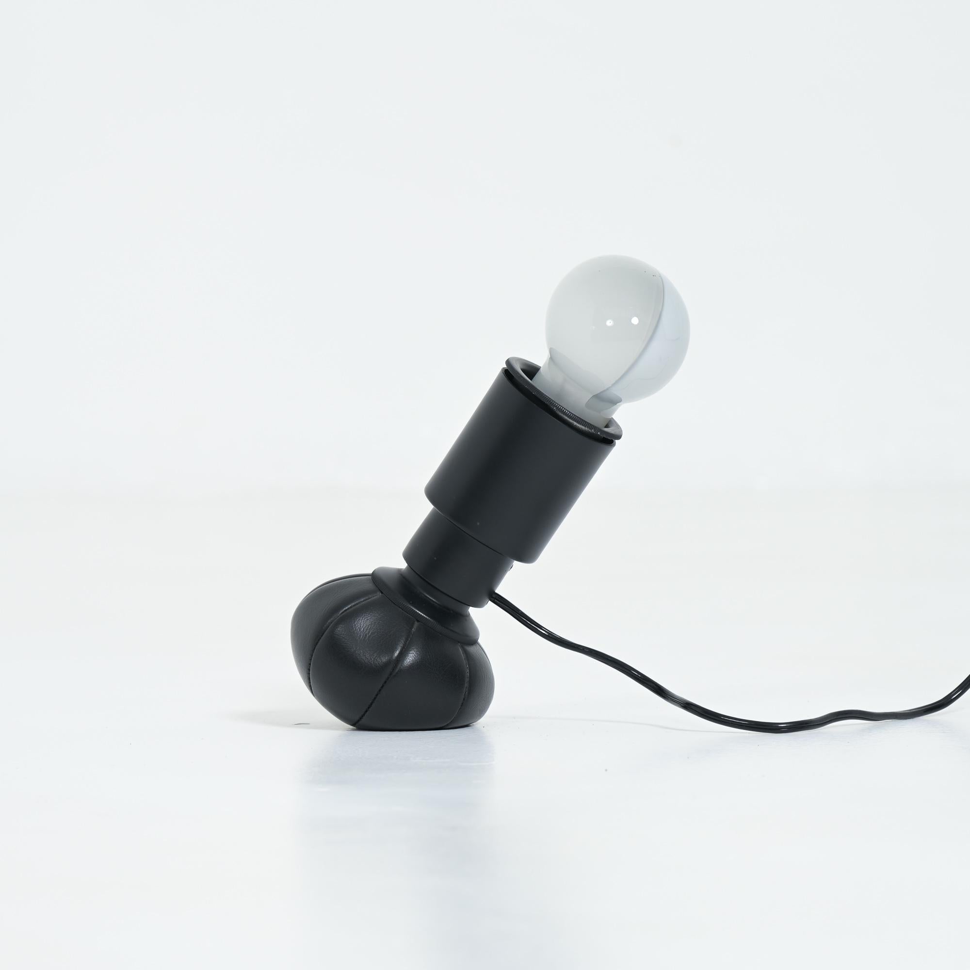 This old original table lamp 600G was designed by Gino Sarfatti for Arteluce in 1966.
The lamp is made of black lacquered aluminum with a black leather base filled with small lead balls which allows the lamp to move in various positions.
This table