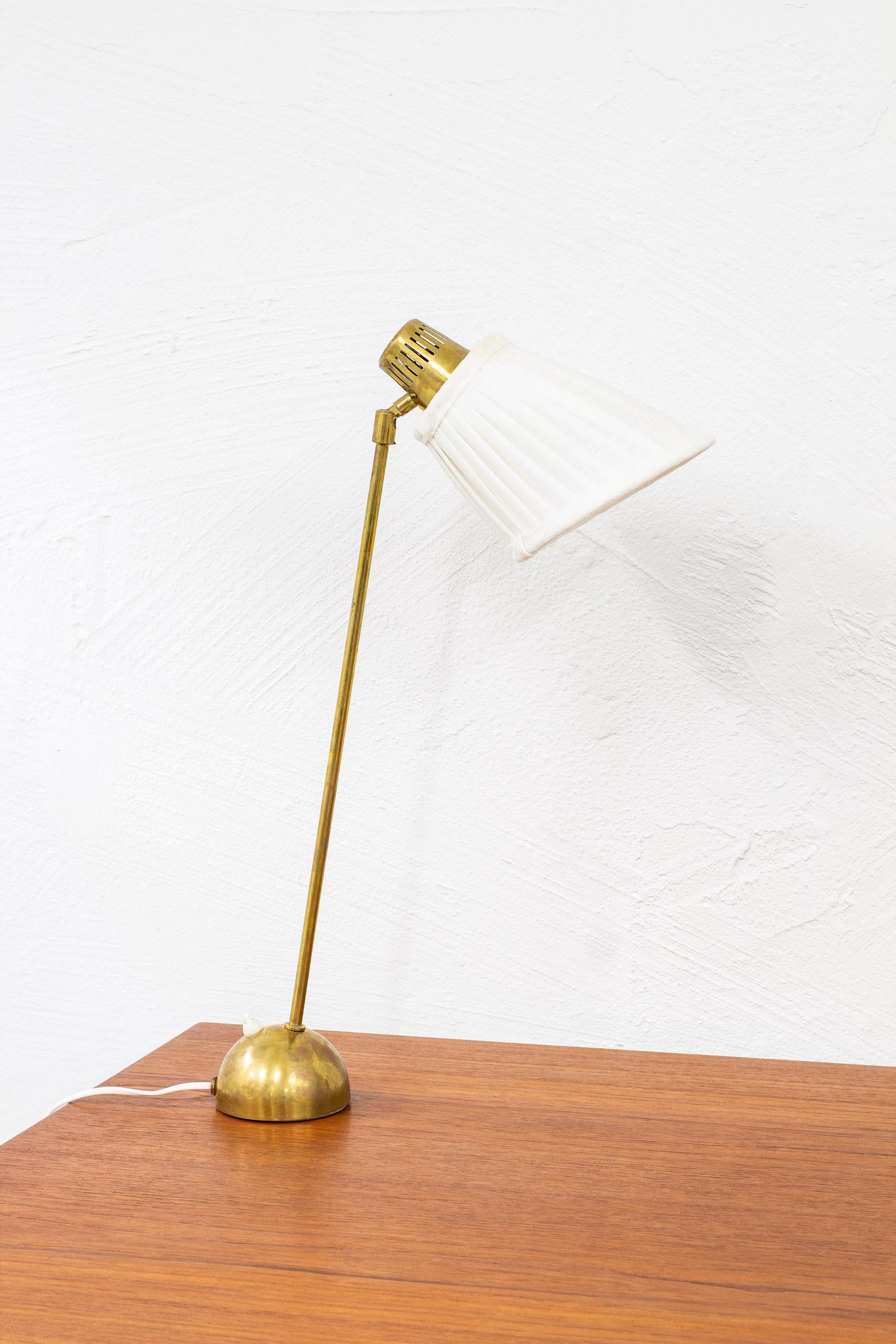 Table lamp model 712 designed by Hans Bergström. Produced in Sweden by Ateljé Lyktan ca 1950. Made from brass with hand sewn, pleated, white fabric lamp shade. Angle of the shade is adjustable. Light switch on the lamp base in working order. Very