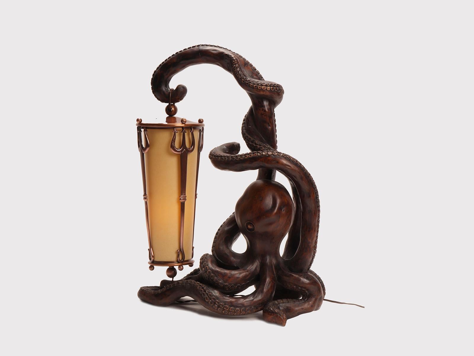 Desk lamp, made out of carved hazel nut wood, depicting an octopus holding a lantern with a tentacle. The lampshade is made of parchment encased by three tridents, made out of copper-plated brass. The socket and switch are in galalite. Aldo Tura