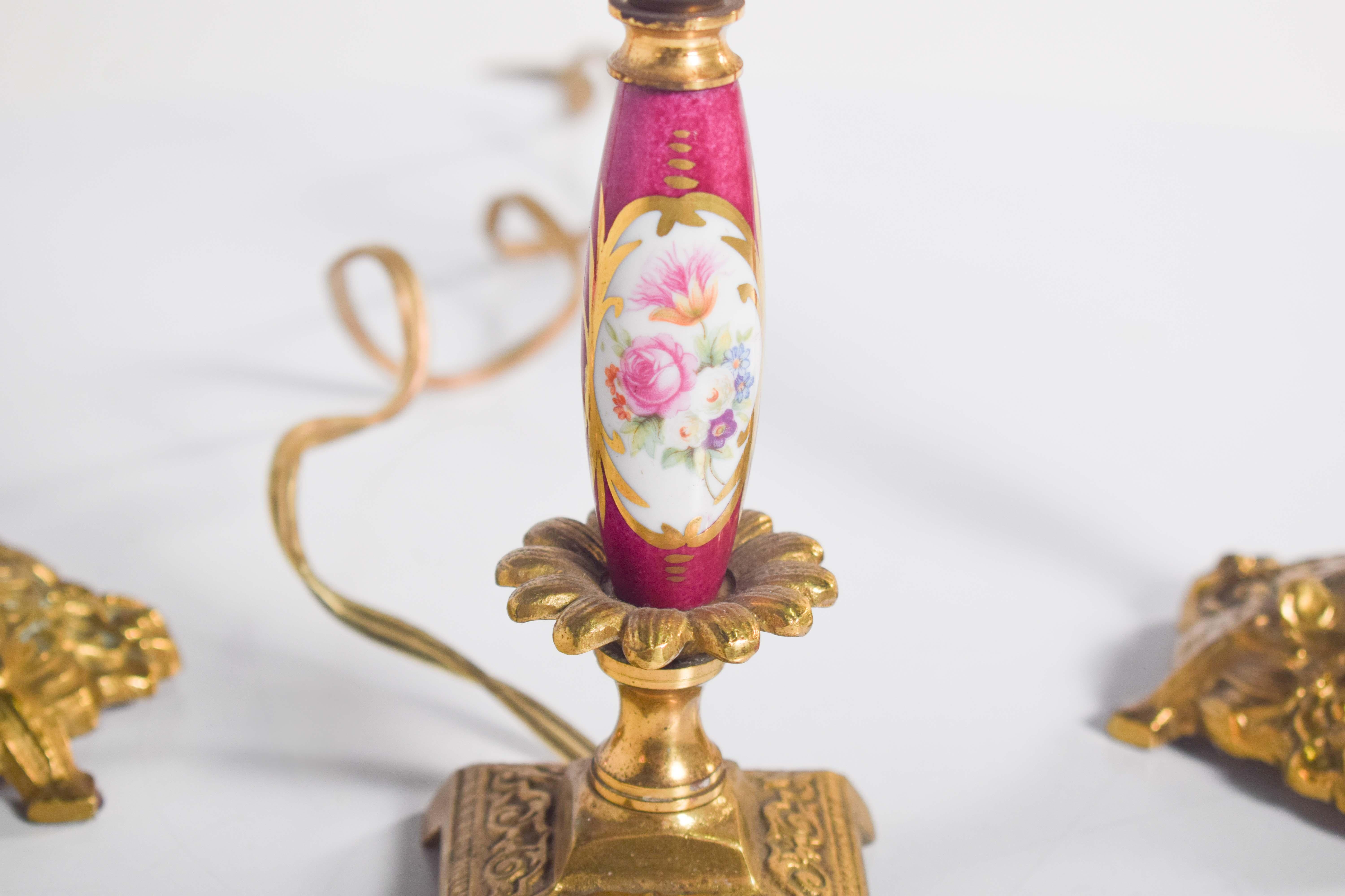 This elegant set consists of a decorative electrified lamp accompanied by two matching chandeliers, all designed to resemble classic candlesticks. The base and candlestick portions of the pieces are crafted from intricately detailed, gilded metal,