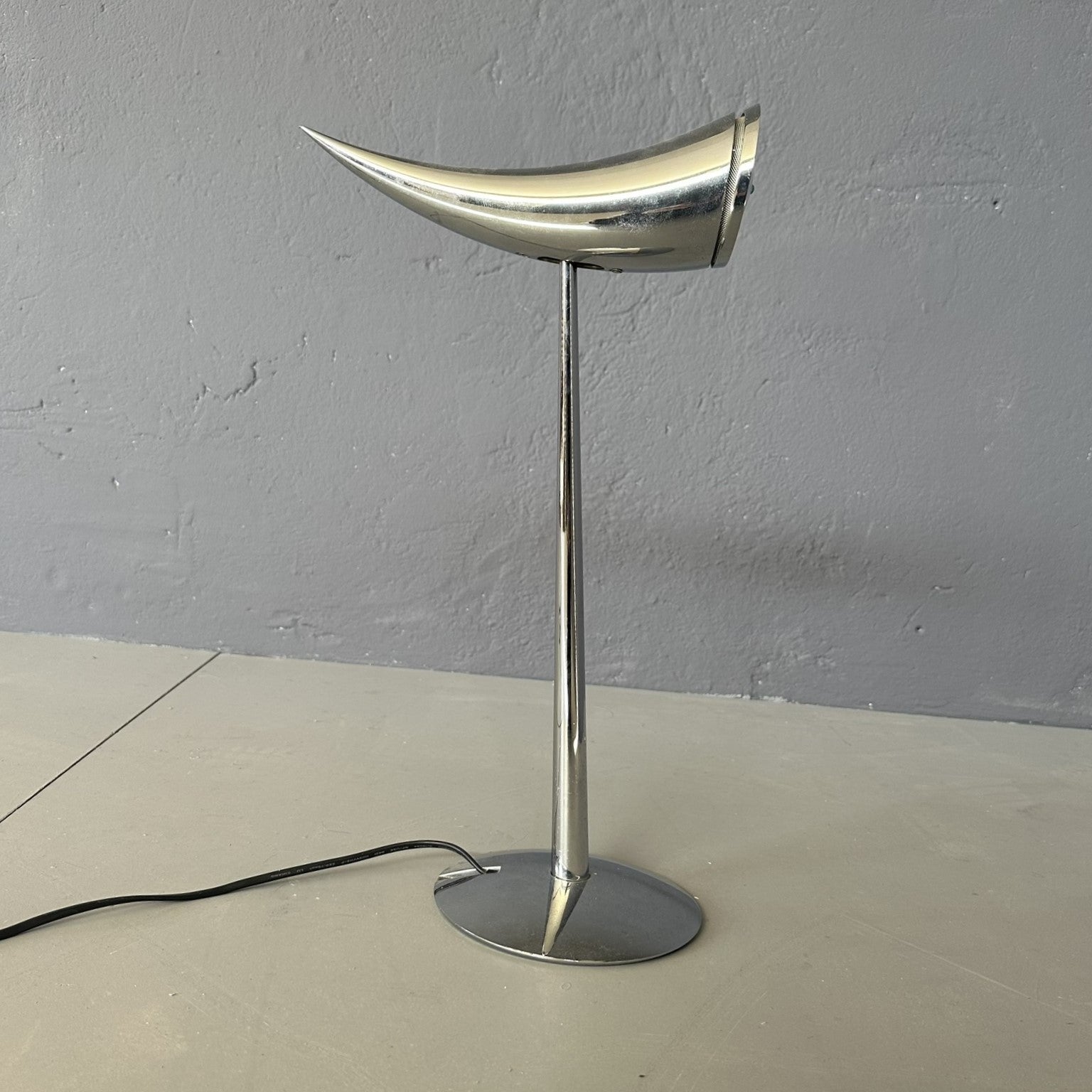 The 'Ara' table lamp, designed by Philippe Starck and made by Flos, takes its name from the designer's daughter.
It is a table lamp with direct adjustable light, with bold lines.
The chromed steel structure, with pressed glass front screen.
The On