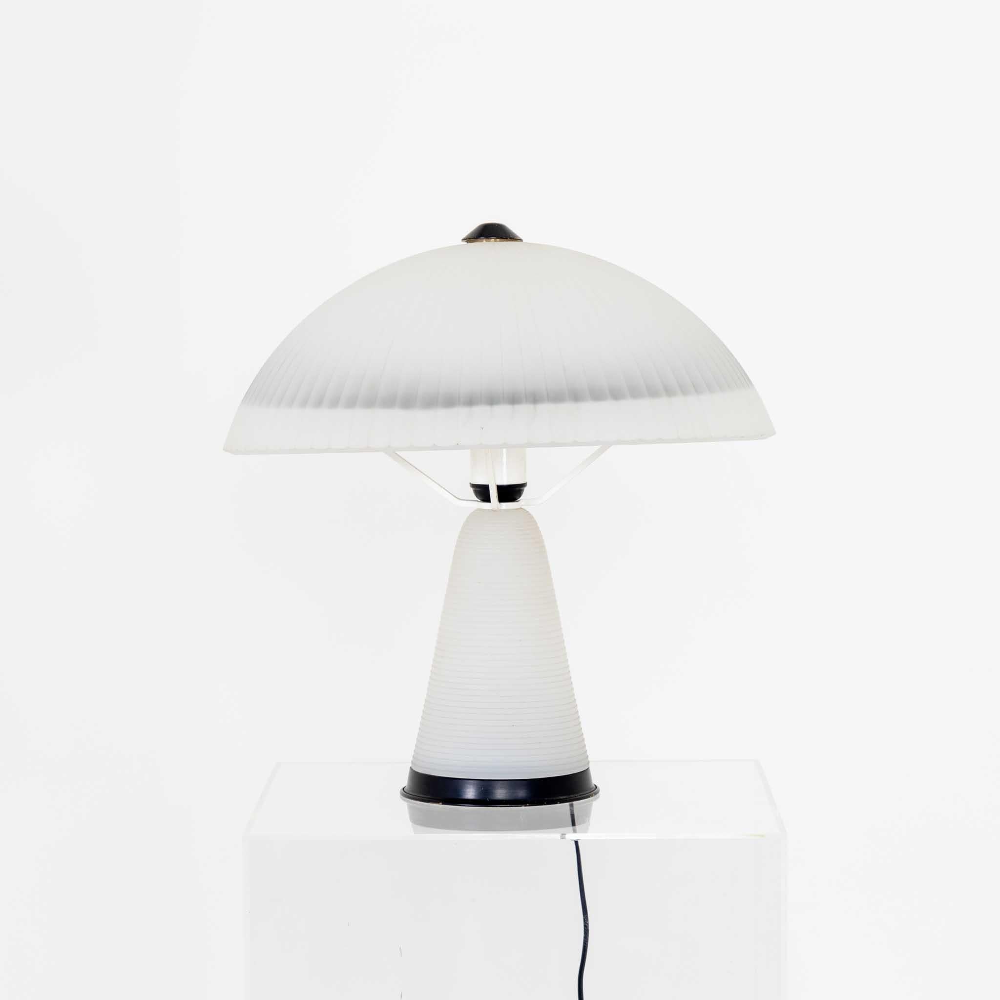Mushroom shaped table lamp made of wavy opaque glass with black mounts.