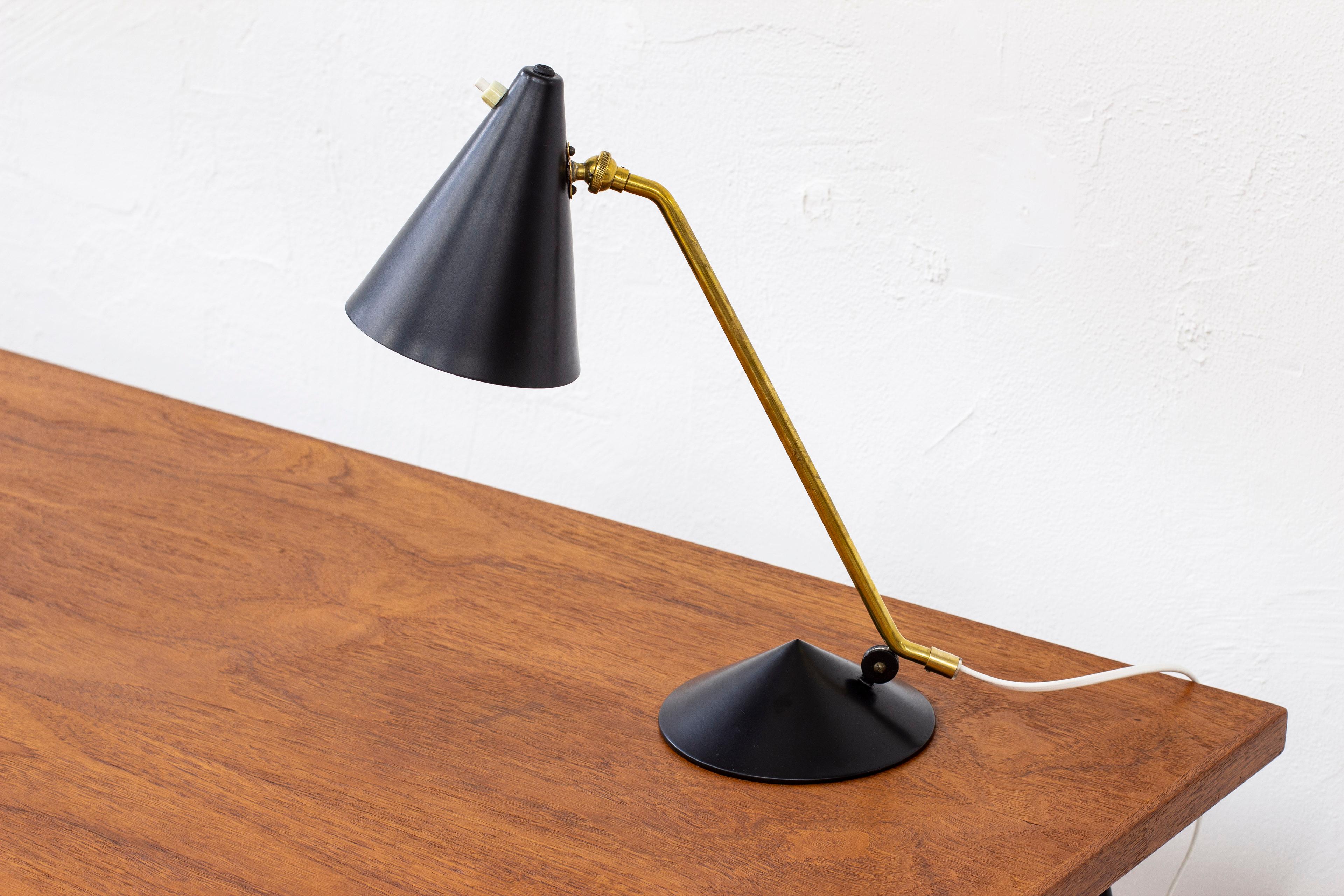 Table lamp attributed to Svend Aage Holm Sørensen. Produced in Denmark during the 1950s, likely produced by Holm Sørensen & Co. Made from brass and black painted metal. Two adjustable shades. Light switch on the shade in working order. Good vintage
