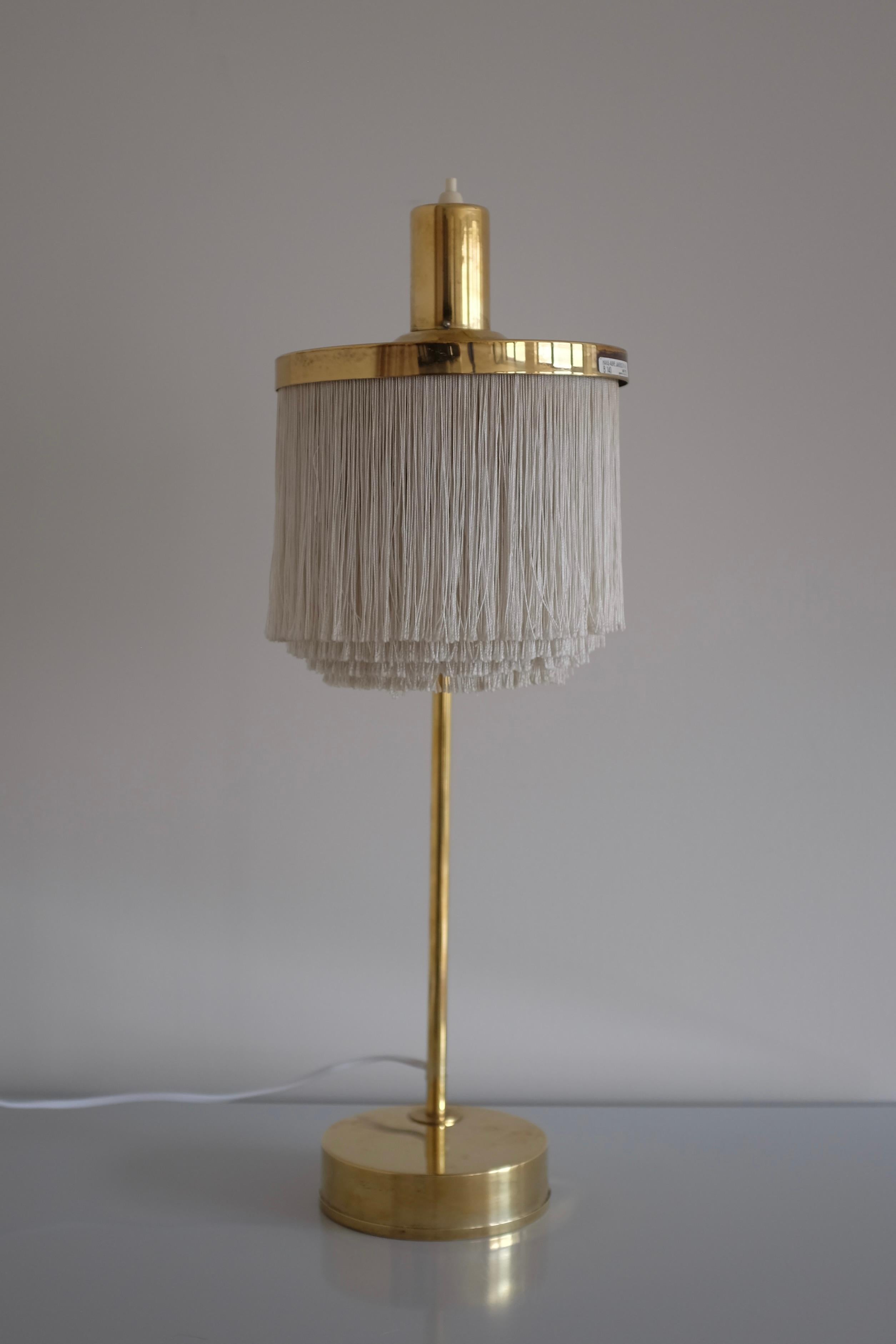 Iconic Fringe and Brass Table Lamp B-140 by Hans Agne Jakobsson. Manufactured in the late 1960s and part of one of Hans Agne Jakobsson most famous collections where the lamp shade consist of silk fabric fringes. Age appropriate wear with patina to