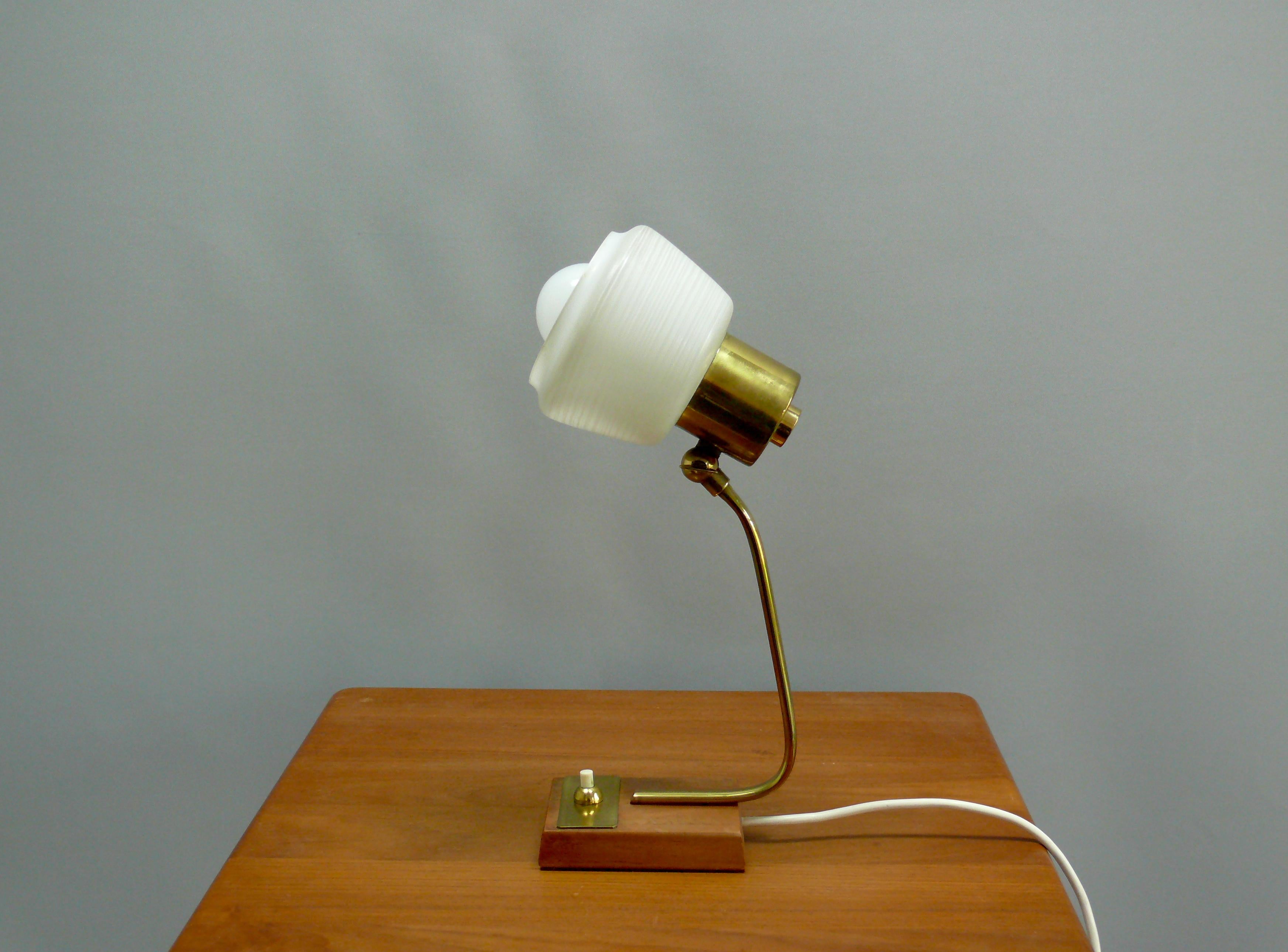 Well-preserved table lamp from the 1960s in Scandinavian style with a teak base and brass holder. The textured opal glass shade – satin white with a delicate radial pattern – emits pleasant, glare-free ambient light. The brass arm and push-button