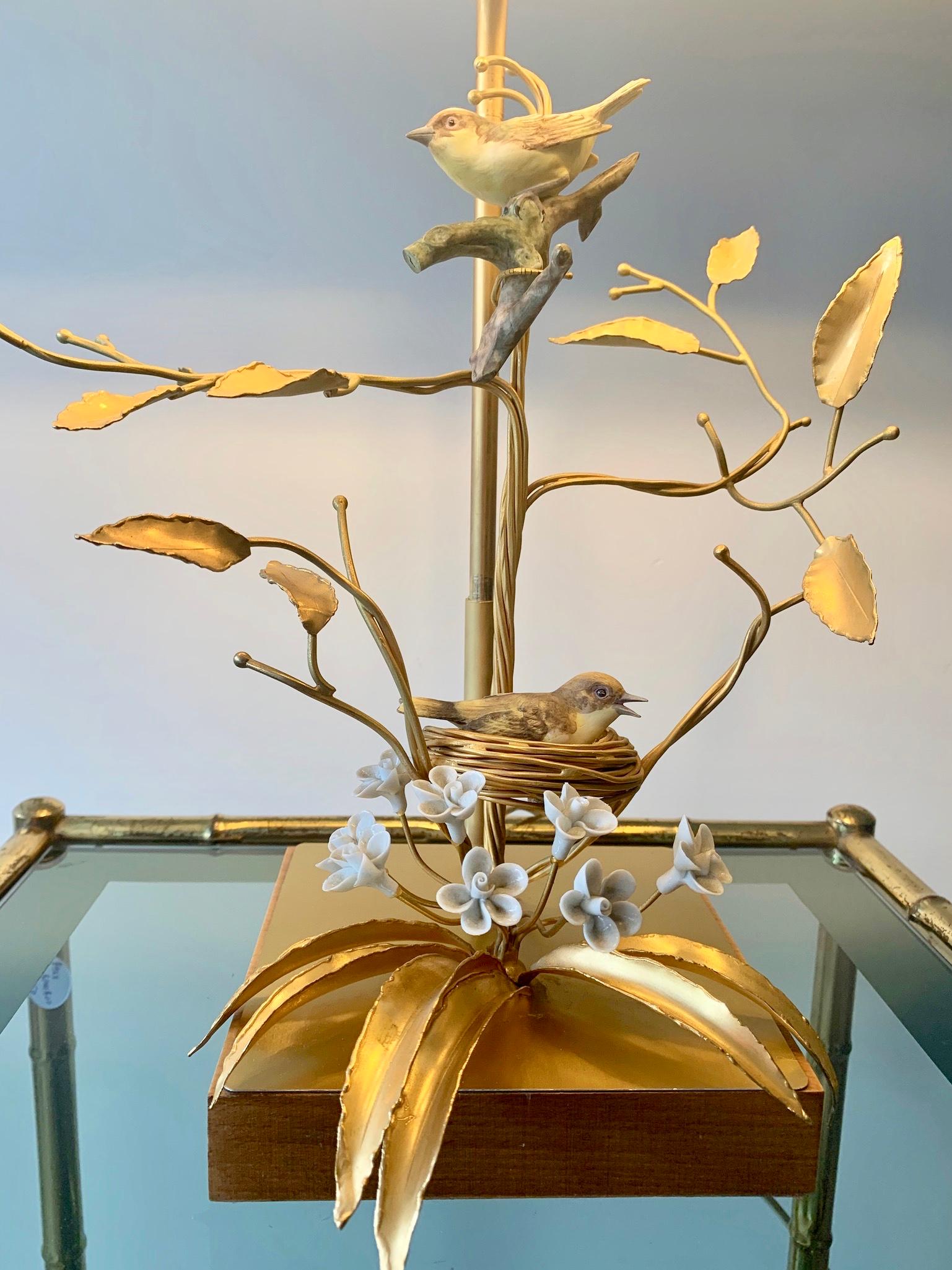 Superbe lampe de table de style Holywood Regency. Base en bois avec un travail complexe de métal doré représentant des branches d'arbre tenant un nid d'oiseau. Les oiseaux et les fleurs sont en porcelaine biscuitée.
 
Le pied de la lampe est