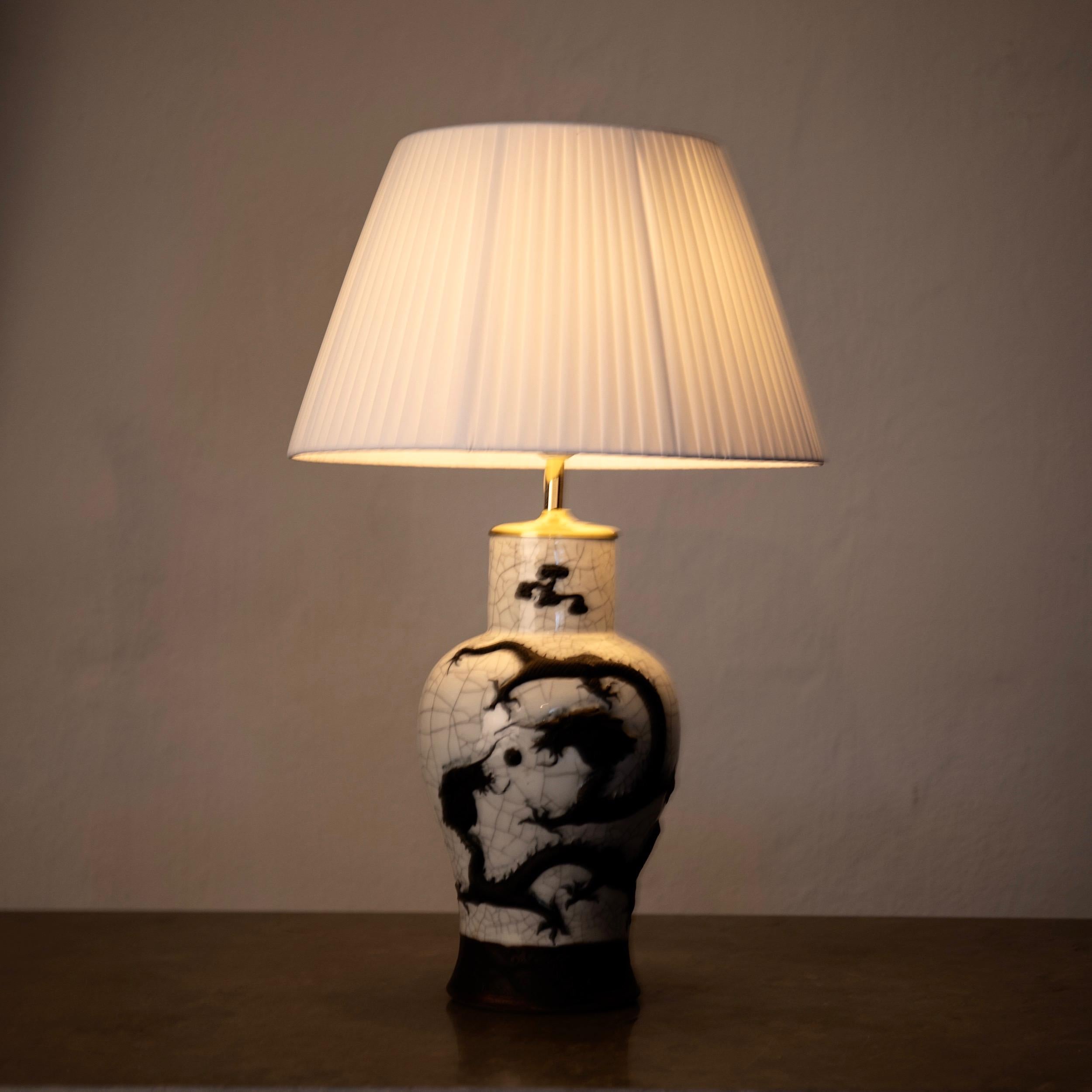 Table lamp black and white porcelain, China. A stunning table lamp in a white porcelain with dark bronze dragons. Height without shade: 17.5 inches. Diameter of foot 6 inches.