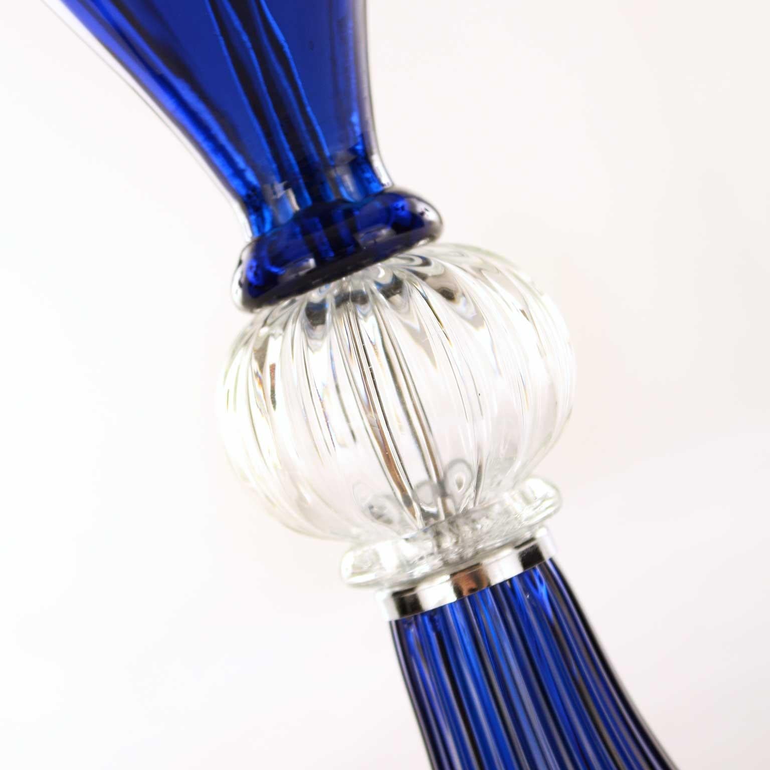 This table lamp is in artistic blue and transparent Murano glass, the lampshade is in white cotton with blue trimmings.
The handcrafted soul of our lighting products is reinvented every time we start a new project, when we are confronted with