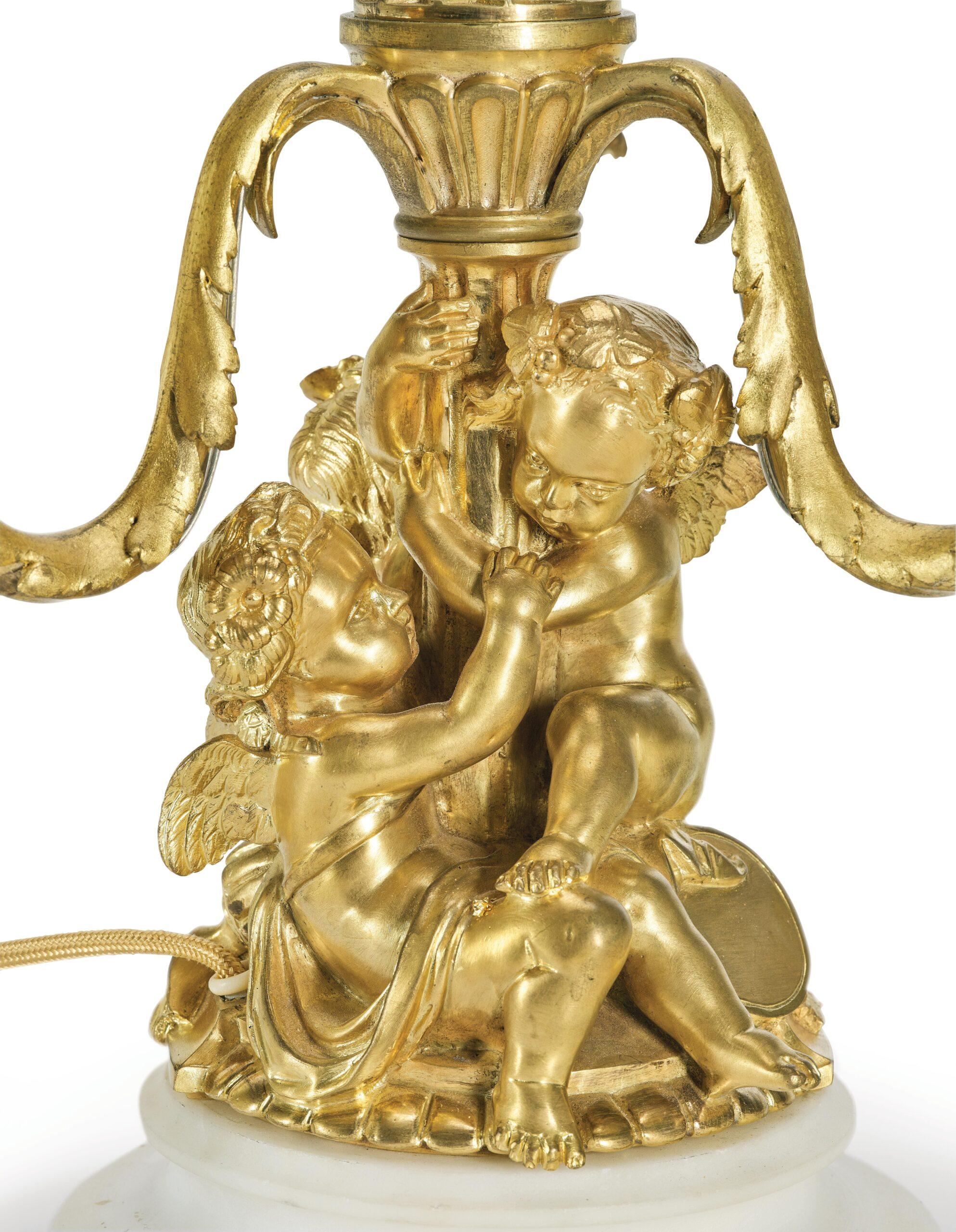So-called “Lampe Bouillotte”, after Clodion, France, late 19th century.
Ornamentally decorated bronze shaft with putti motifs, finely gilded, set on a moulded marble base with beadwork decoration. Electrified with three lights/flames.