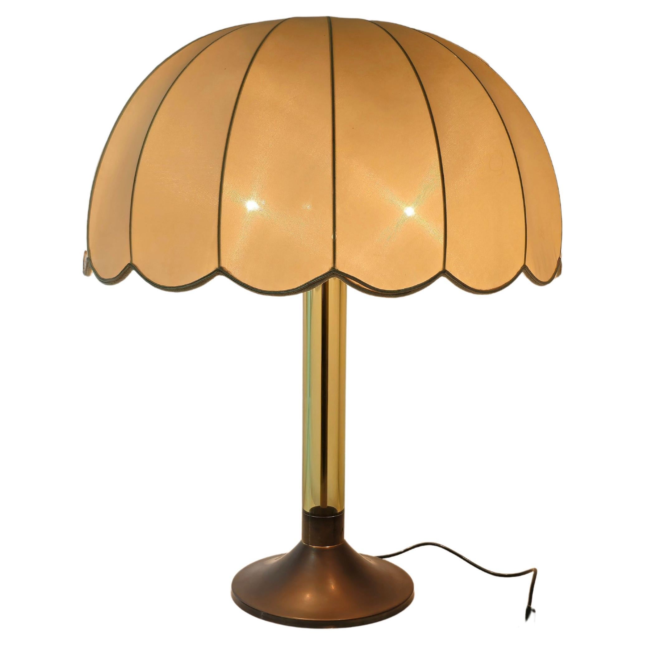 Table lamp of considerable dimensions produced in Italy in the 60s.
The lamp was made with a burnished brass structure with two directional E27 lights, a tubular plexiglass stem in aqua green tones and a hemispherical lampshade in ivory-colored