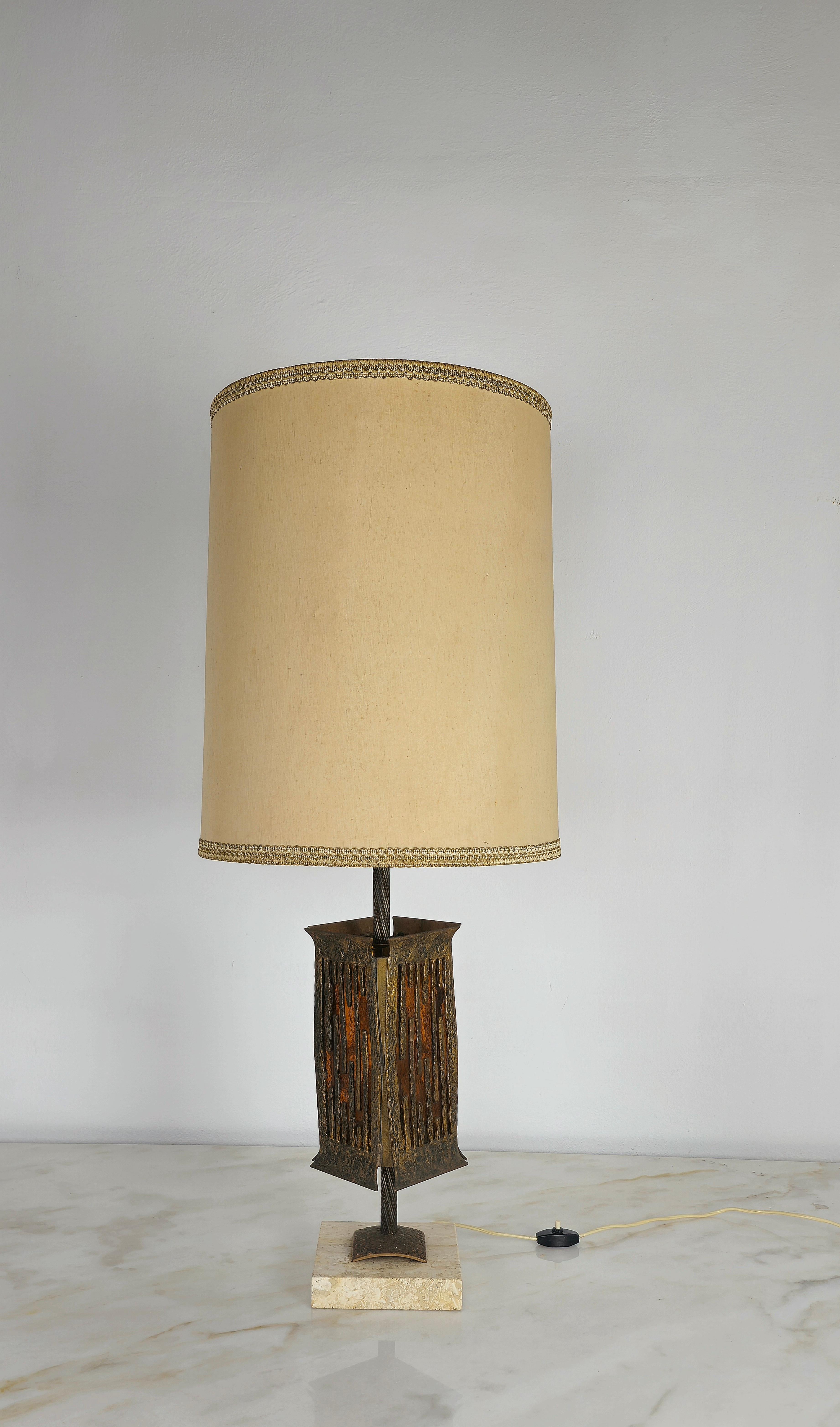 Brutalist table lamp by Albano Poli for Poliarte made in Italy in the 70s.
The lamp has a bronze structure with 2 intermittent lights, the first which illuminates the cylindrical fabric lampshade, and the second illuminates a caramel colored