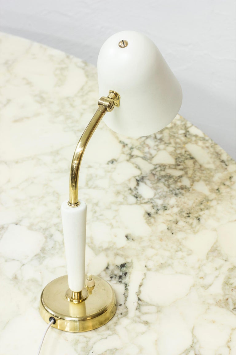 Table lamp designed by Bertil Brisborg. Produced by Nordiska Kompaniet in Sweden during the 1950s. Made from polished brass, wood and aluminum shade in crème white. Light switch on the base in working order. Adjustable in angle and to the sides.