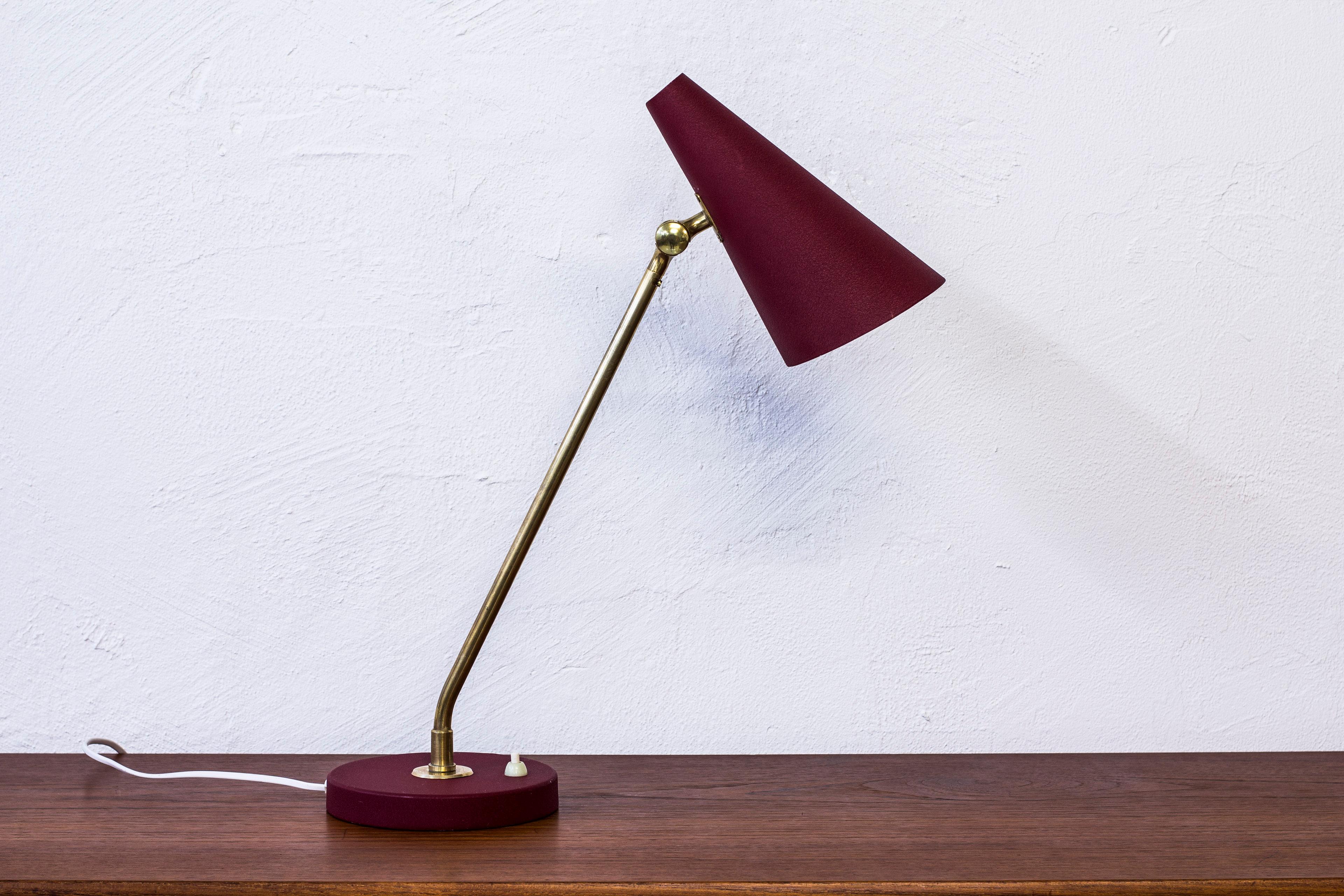 Table lamp designed by Bertil Brisborg. Produced by Nordiska Kompaniet in Sweden during the 1950s. Made from metal with original red lacquer and polished brass. Light switch on the base in working order. Adjustable in angle and to the sides. Very