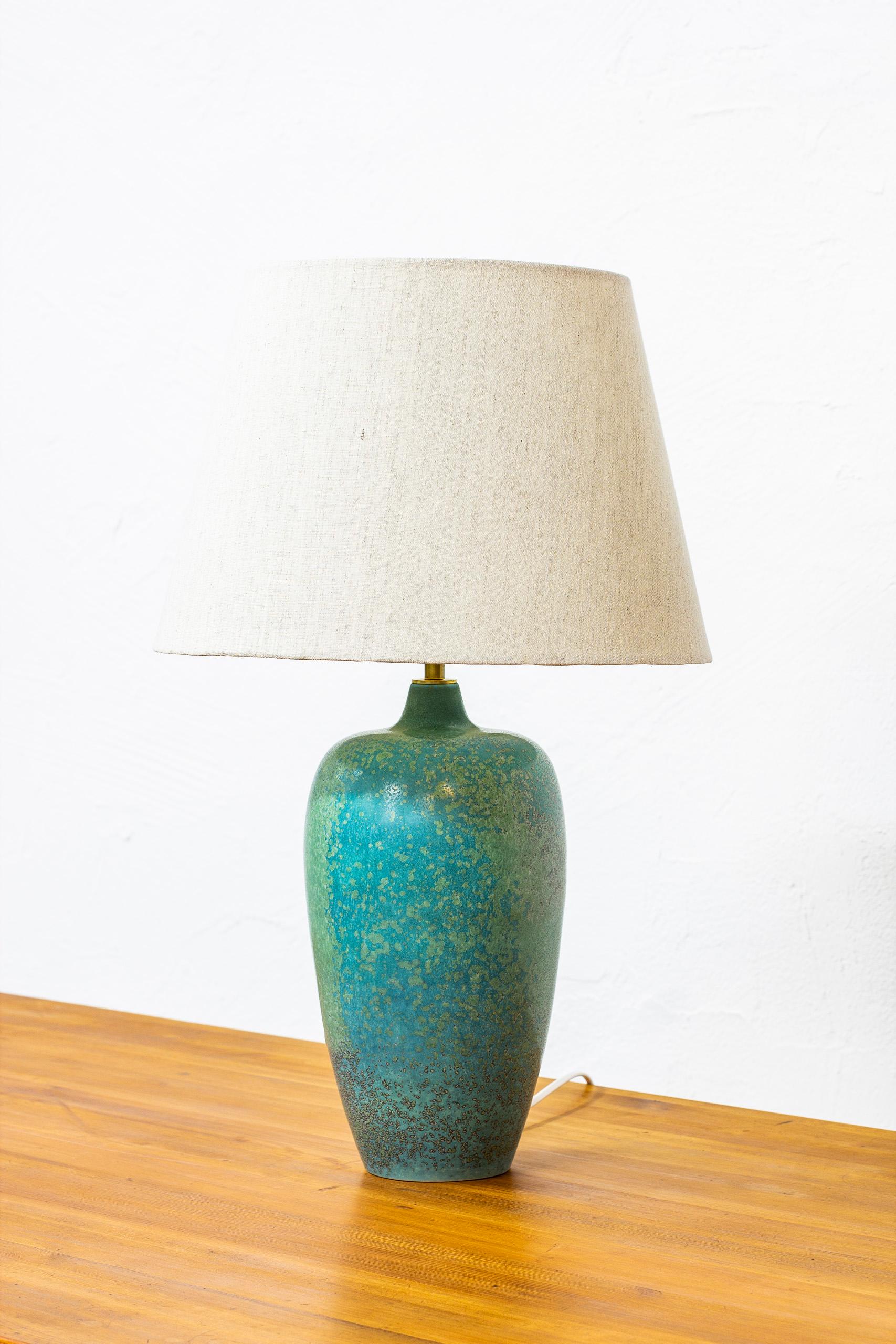 Table lamp designed by Carl-Harry Stålhane. Handmade at Rörstrand in the 1950s. Stoneware with turquoise shifting glaze. New linen lamp shade in light grey. Very good vintage condition without damages.