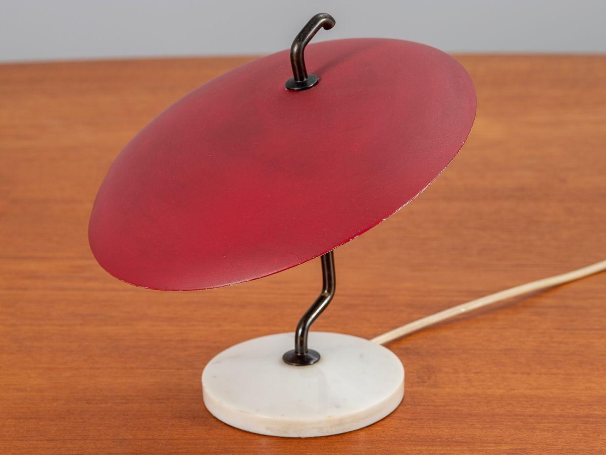 Kleine organische, moderne Tischleuchte, entworfen von Gino Sarfatti für Arredoluce. Verspielter, spitzer Farbton in einem auffälligen Karminrot. Auf einer Stange aus Rotguss balancierend, getragen von einem schweren Marmorsockel. In wunderbarem