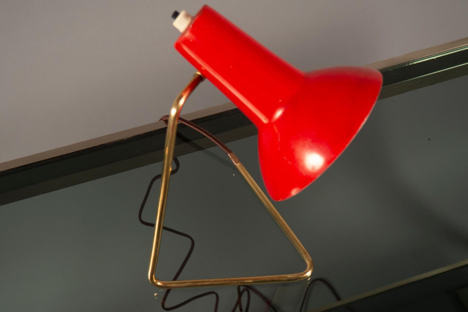 Table lamp with a triangular bent brass holding a red painted lamp shade. Original label.