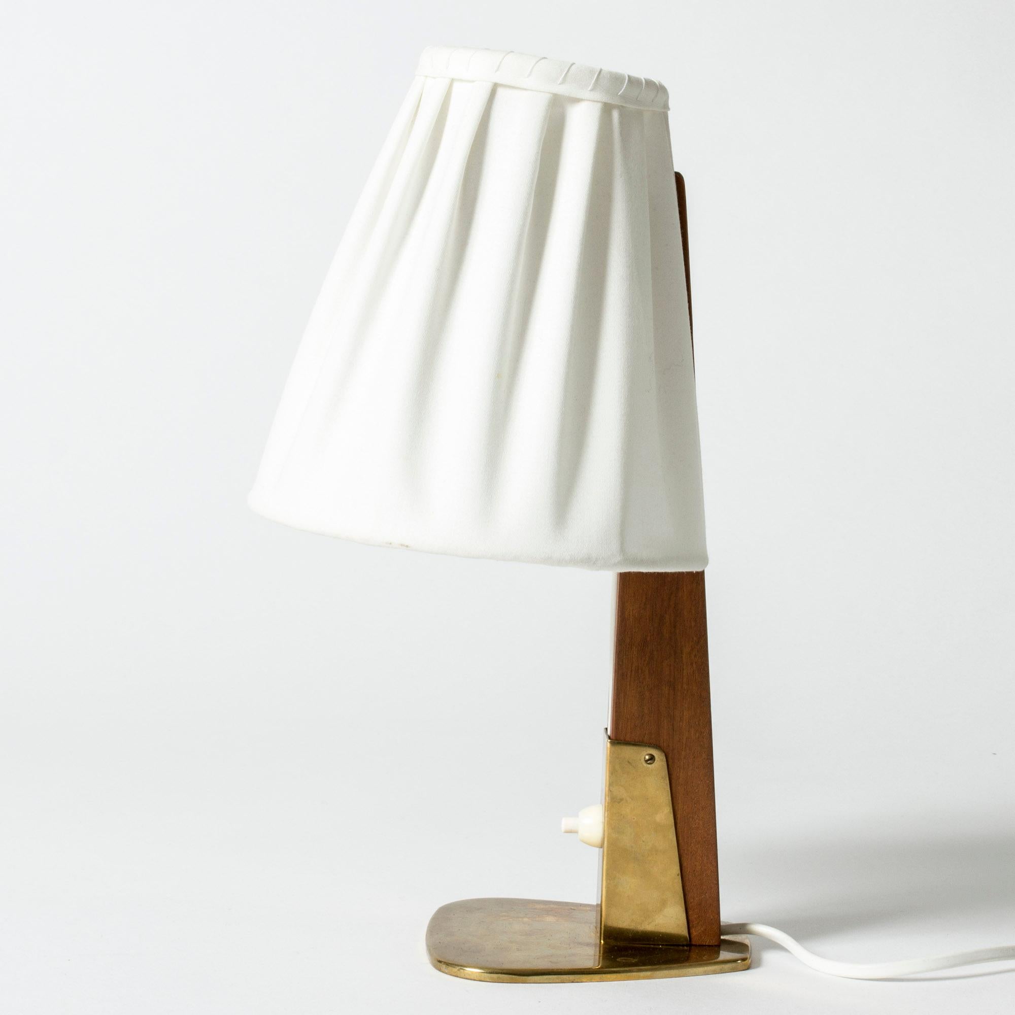 Neat table lamp by Hans Bergström for ASEA, made from brass with a teak stem, pleated white shade. The electrical cord runs visibly through the wood, an elegant detail. Wide brass base.