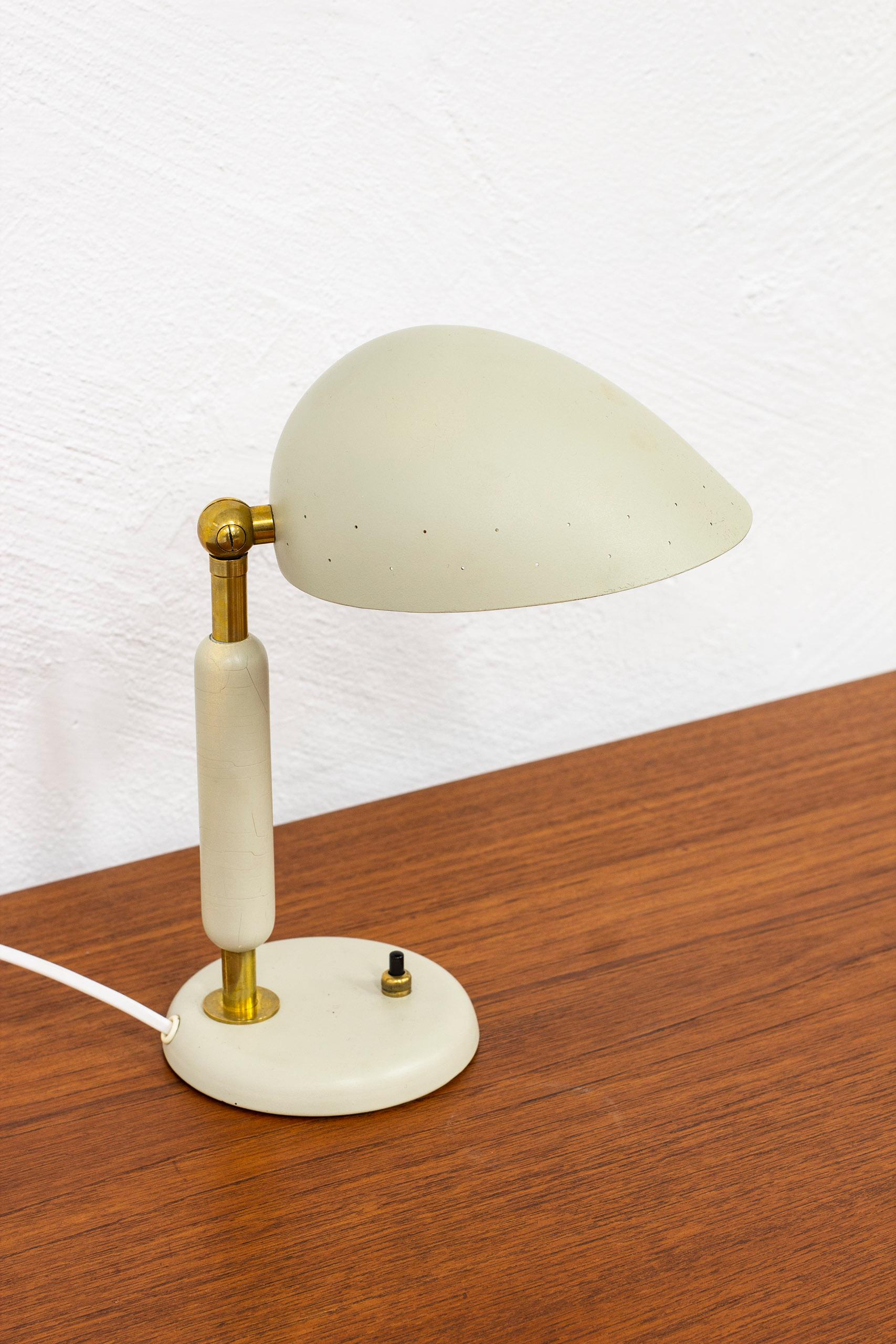 Table lamp designed by Harald Notini. Produced in Stockholmn, Sweden by Böhlmarks lampfabrik during the 1940-50s. Made from brass, lacquered wood and aluminum. Light switch on the base in working order. Adjustable shade. Good vintage condition with