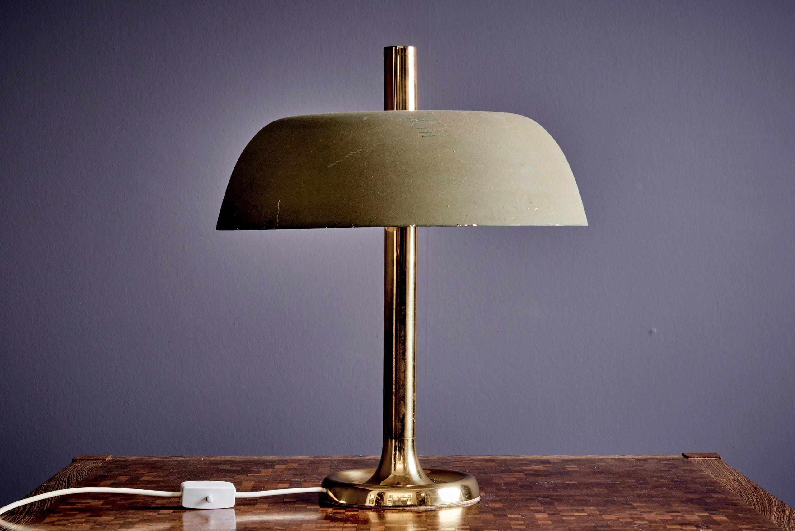 Esta lámpara de sobremesa vintage, diseñada por la renombrada Hillebrand Lighting en la década de 1960, presenta una tija y una base de latón, que ofrecen un contraste cálido y elegante con la gran pantalla de metal liso. La lámpara tiene una