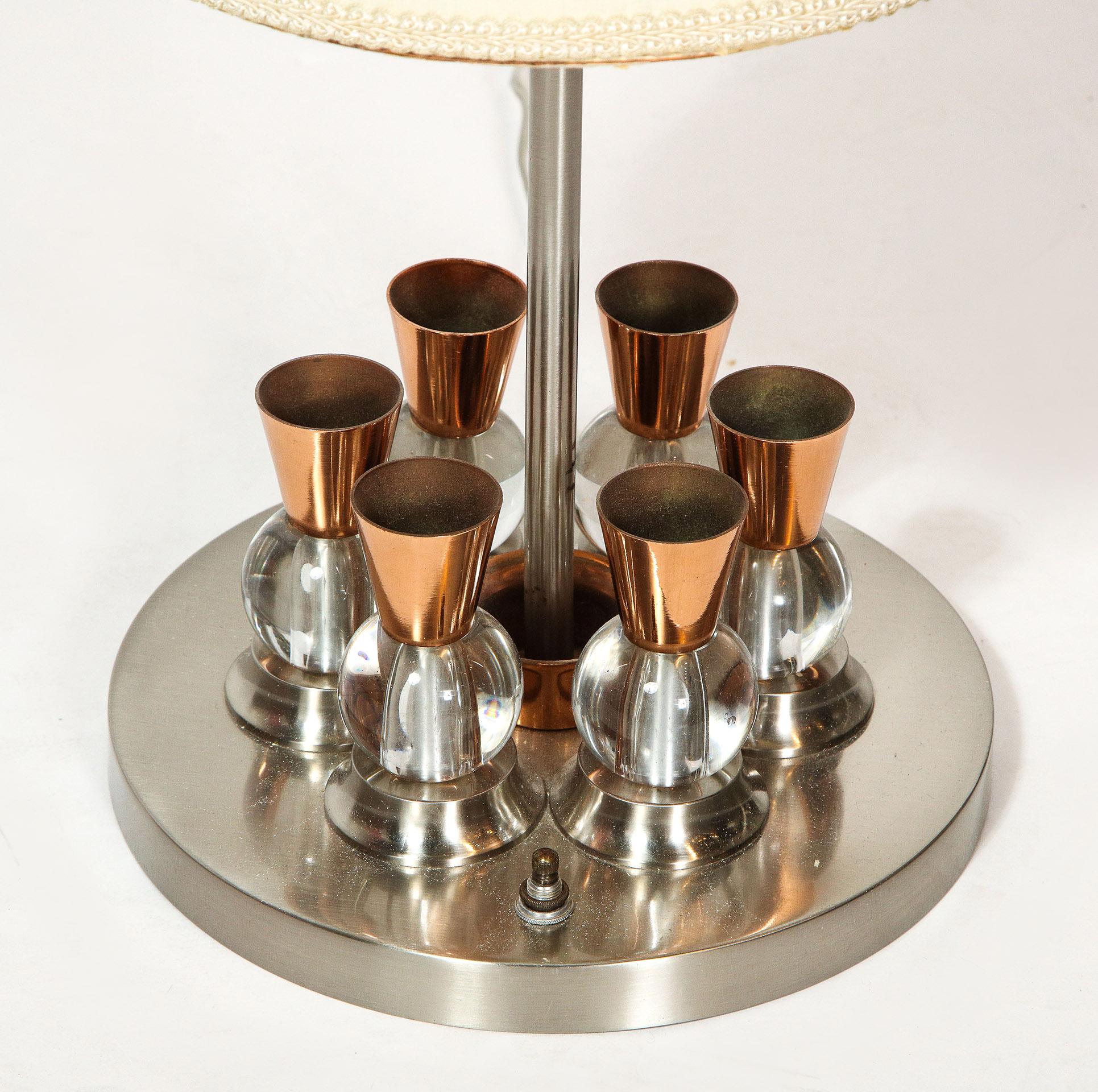 A French chrome, copper and glass lamp, attributed to Jacques Adnet

With six copper cones above glass spheres encircling the standard, on a circular base with its original cylindrical shade.
 
