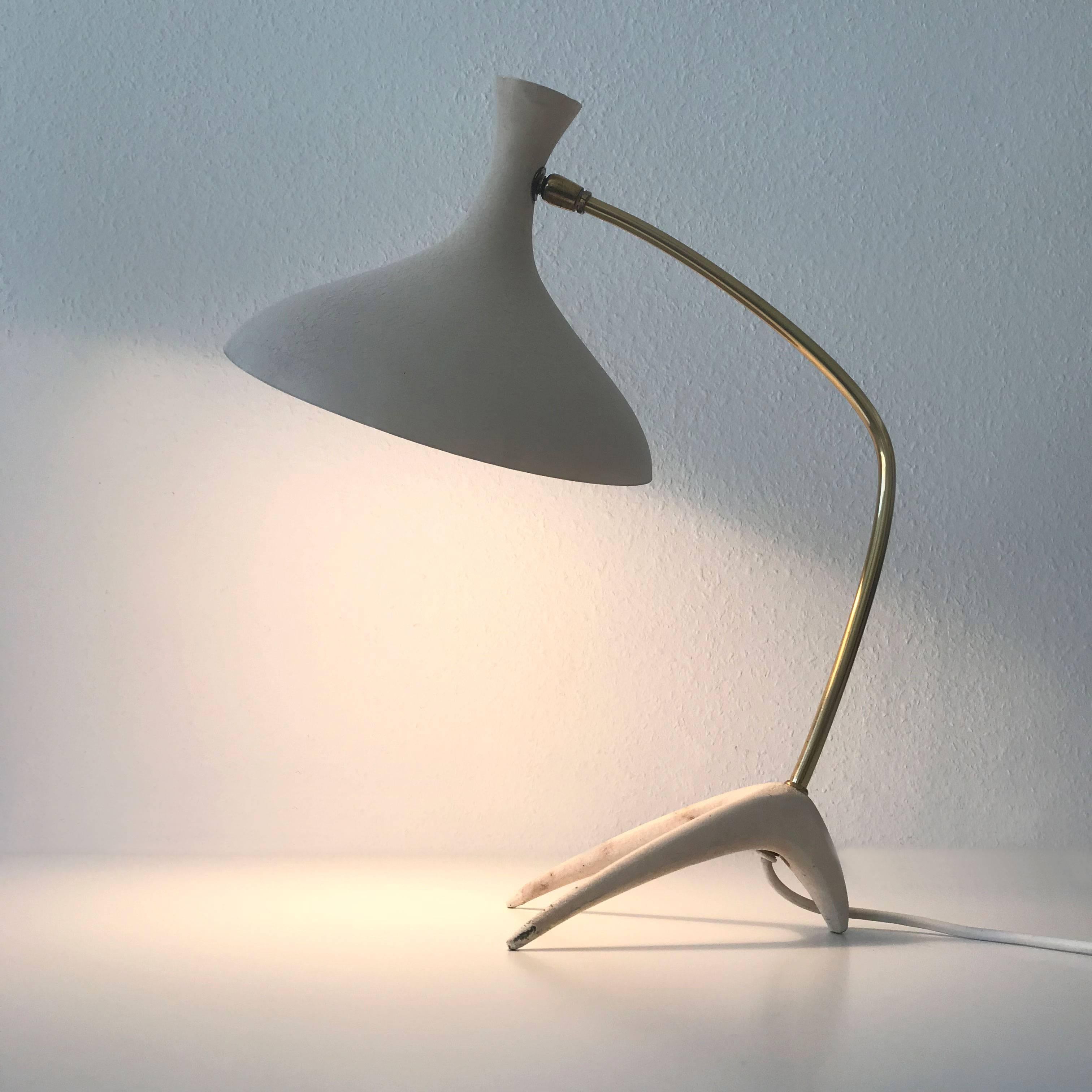 Stunning and rare Mid-Century Modern table lamp with adjustable shade. Designed by Louis Kalff for Gebrüder Cosack, 1950s, Germany.
This elegant table lamp is executed in brass, in crème-white lacquered aluminium and cast metal base.
It is