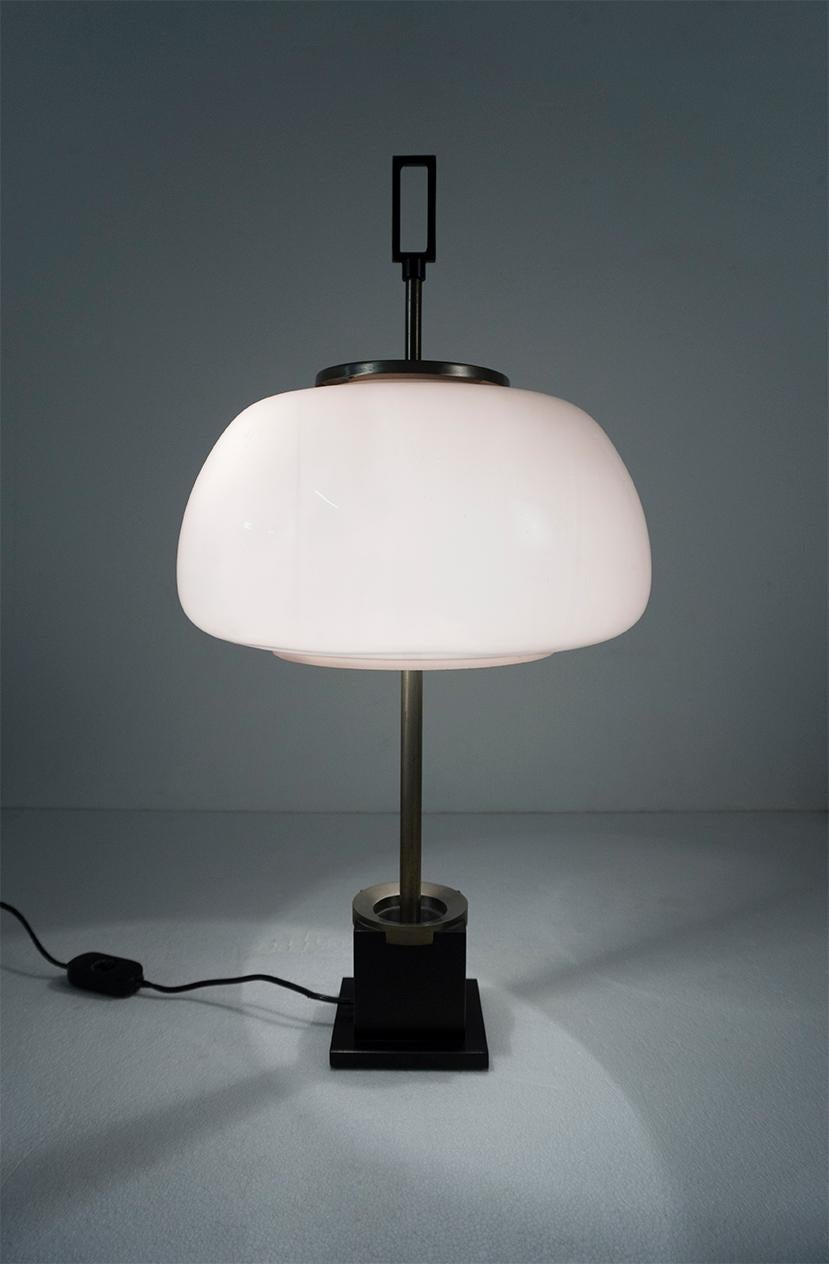 Table lamp with a nickel-plated metal construction and an iron cast base lacquered in black.
The reflector is made of opaline rose-colored glass. 

Dimensions: H 53 cm, Ø 28 cm
Design: Oscar Torlasco, circa 1960
Manufacturer: Lumi, Italy.