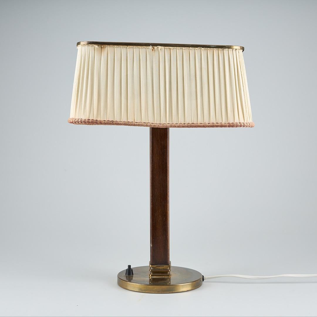  Struttura in ottone e teak, paralume in tessuto con 2 prese E27, disegnato da Paavo Tynell nel 1940 per Taito Oy, modello 5066. Condizioni originali non restaurate. 