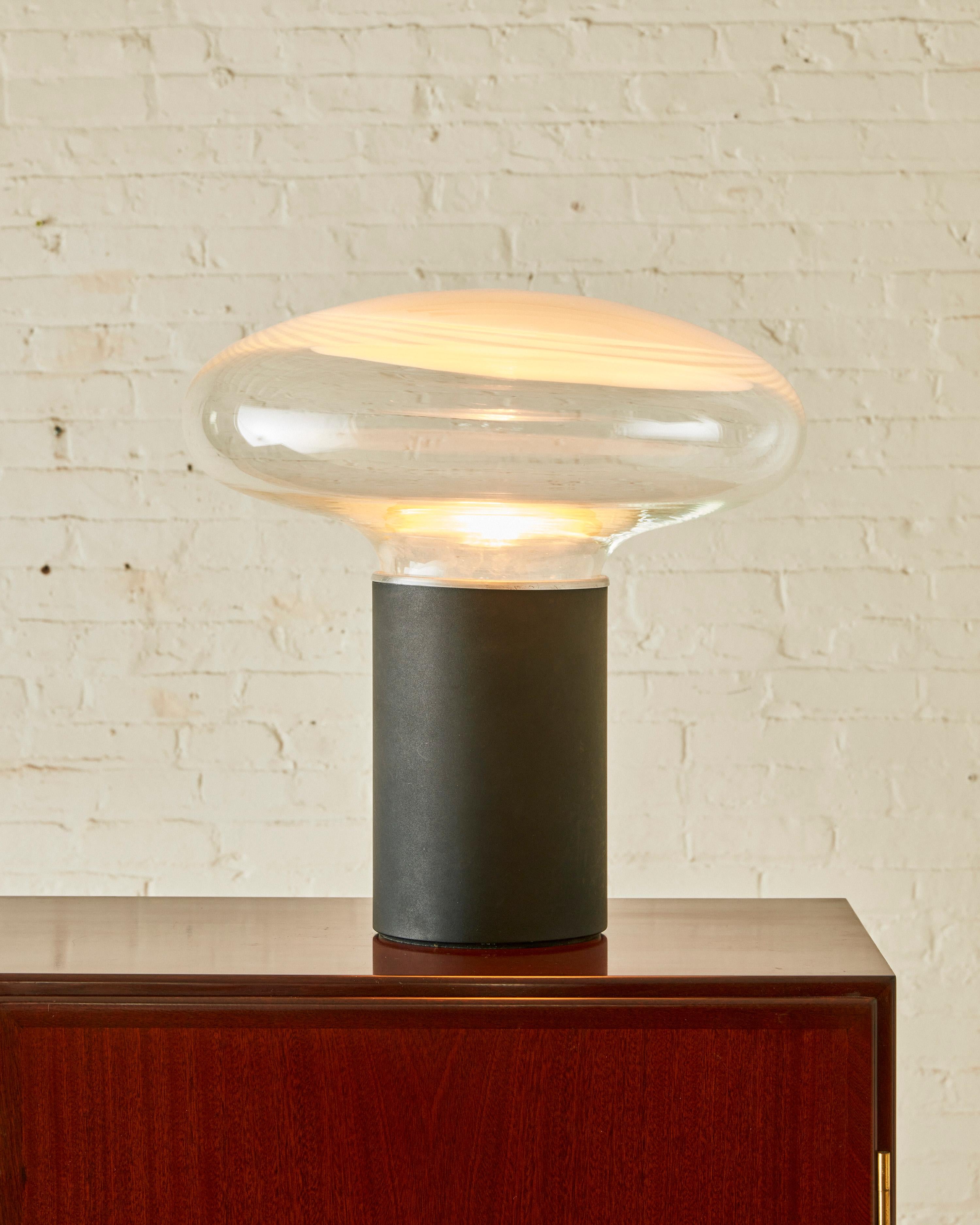 Table Lamp by Roberto Pamio for Leucos ( Model Gill 45 ) featuring a black metal base and an Murano art glass shade. 

Roberto Pamio works intensively in the design world internationally. With the Pamio Architectural Studio and Pamio Design in