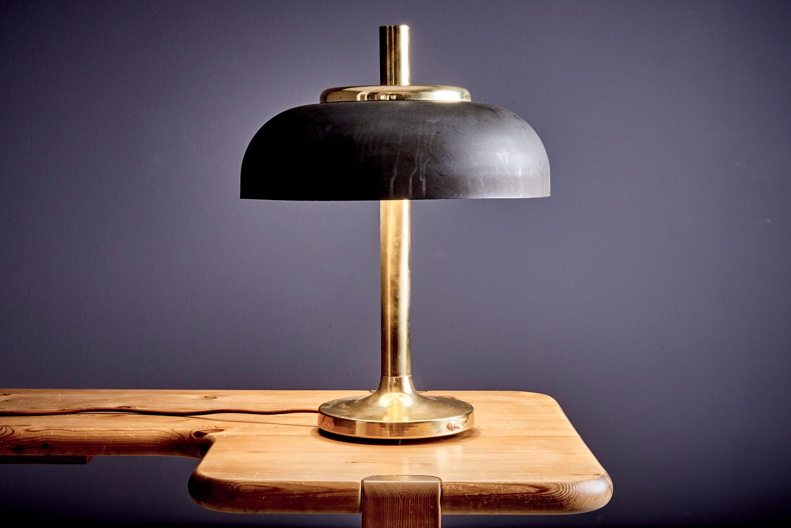 Mid-century table lamp by Sölken Leuchten, Germany, 1970s. It features a polished brass base and stem paired with a matte black metal shade that reveals a subtle greenish hue. The shade’s white interior provides soft, even illumination, supported by