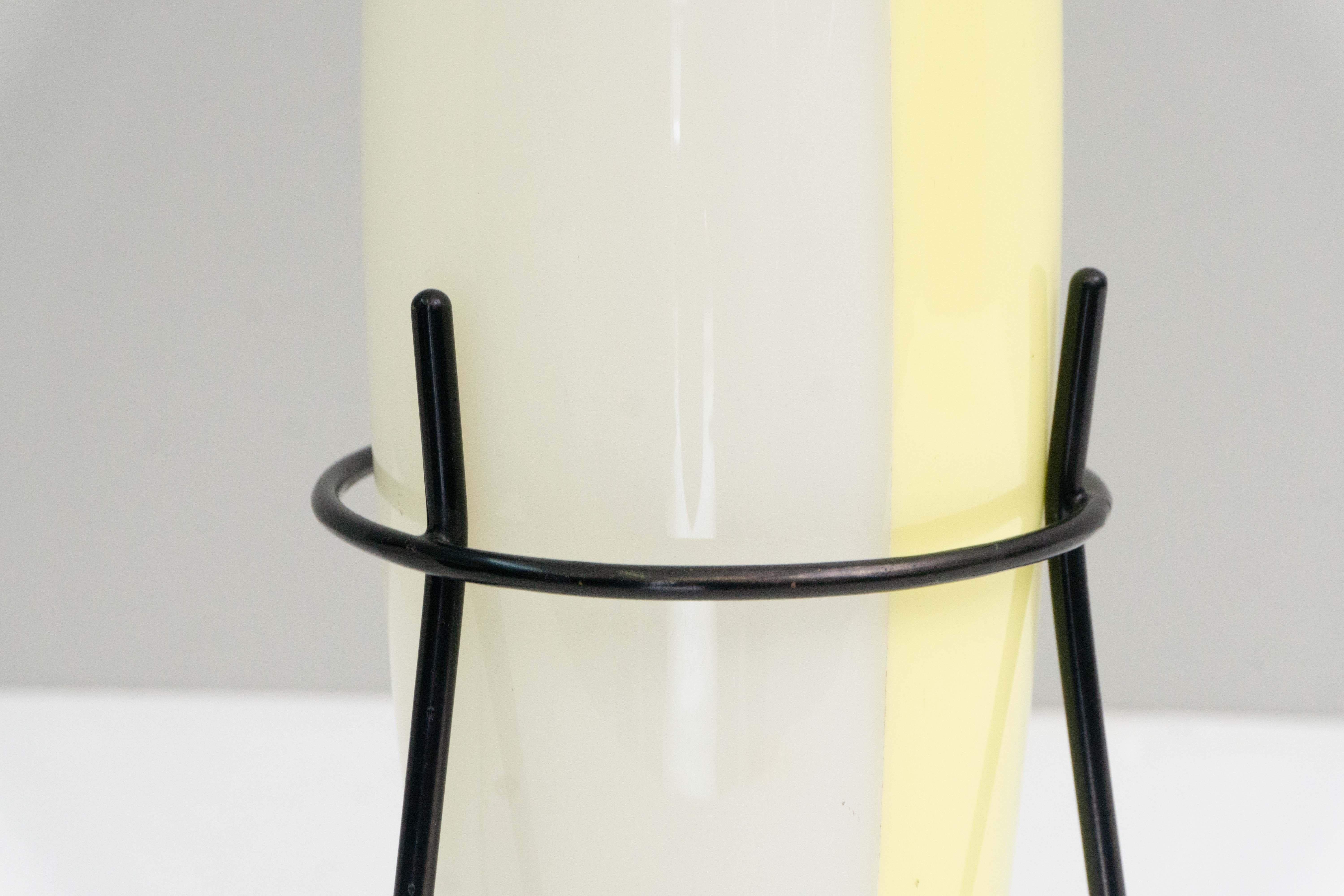 This extraordinary and elegant table lamp by Stilnovo, Italy, was designed around 1950.
The lampshade is made of acrylic glass, white/yellow in color, the construction is made of black metal, which ends in brass feet.