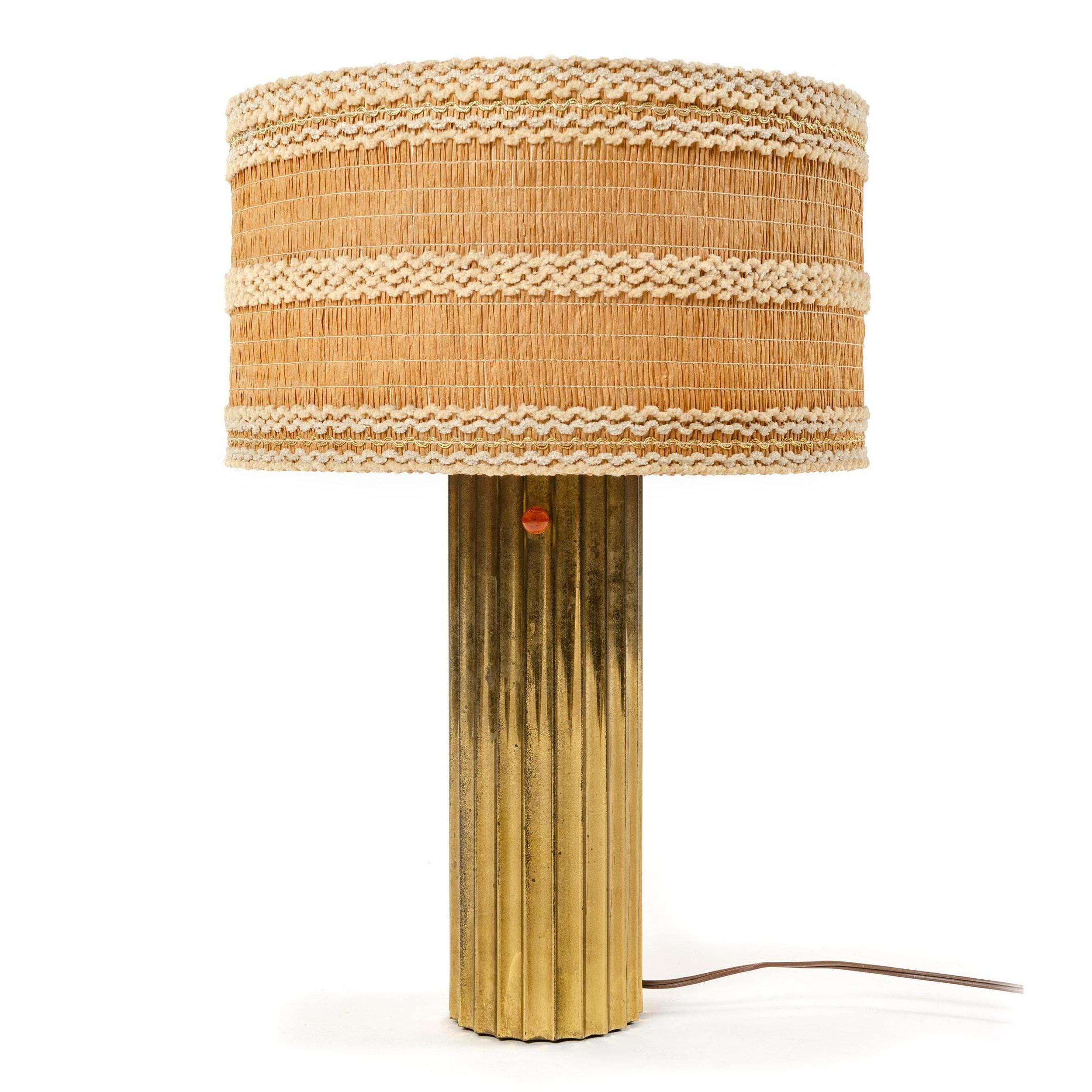 A corrugated patinated brass table lamp with a glass diffuser shade to direct light upwards and a fabric shade to soften the glow.