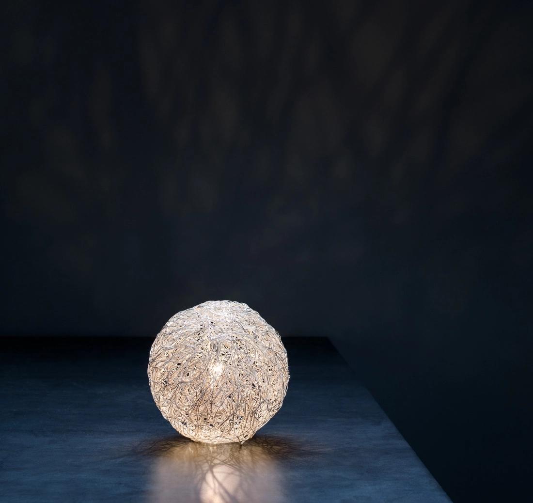 Le Sweet Light, conçu par Enzo Catellani, est issu du même parcours créatif que celui qui a conduit à l'emblématique Fil de Fer. Fabriquée à partir de fils d'aluminium façonnés et tissés, illuminés de l'intérieur, elle produit une lueur délicate et