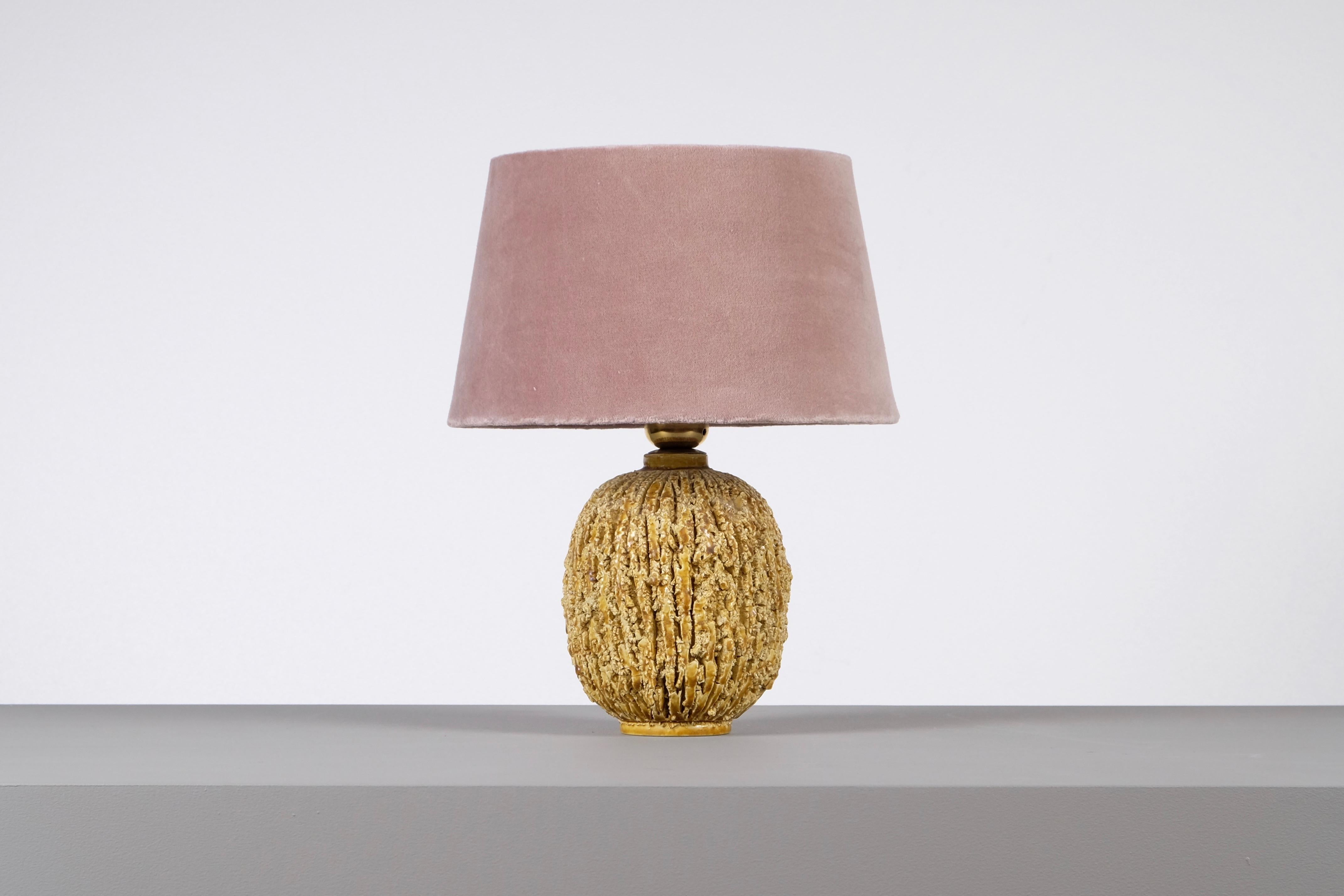 Ceramic lamp in bulbous shape by Gunnar Nylund, composed of chamotte clay and glazed with a gold colored luster glaze. Produced by Rörstrand.
Stamped. Measures: Height including shade 33 cm. New wiring.