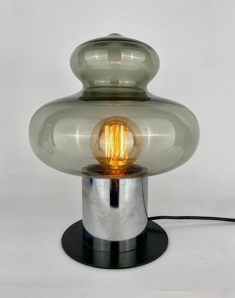 Lampe de table en noir avec un capot en acier chromé et en verre fumé.
Années 1970.