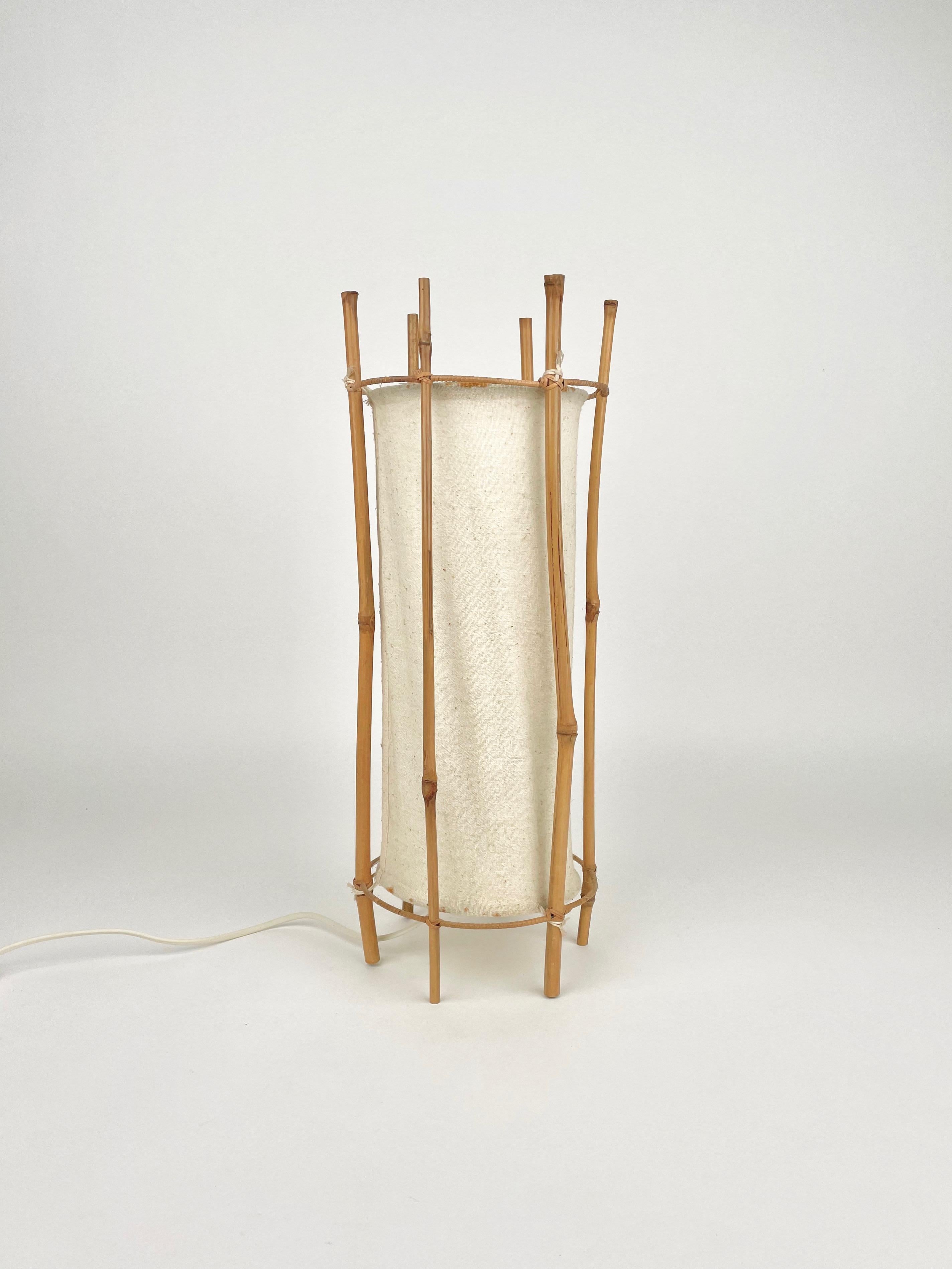 Cylindrical shape table lamp in white cotton featuring structure in bamboo composed of six stems. Attributable to the French designer Louis Sognot, made in France in the 1950s.