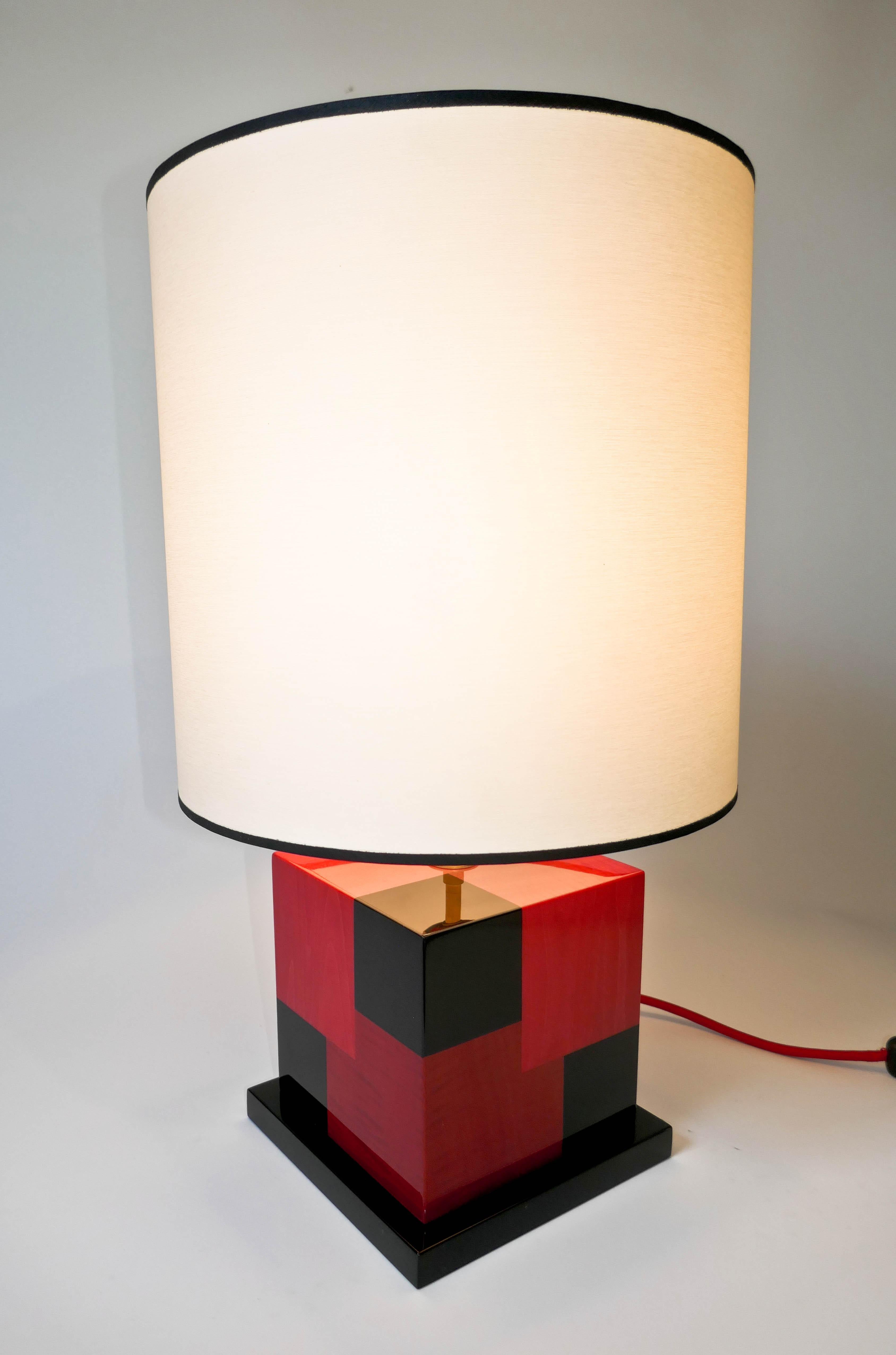 Lampe de table en marqueterie de sycomore teinté noir, rouge clair et rouge foncé.
Fabriquée avec soin dans notre atelier parisien, cette lampe a un effet cinétique utilisant les différentes couleurs pour créer une impression de profondeur. La lampe