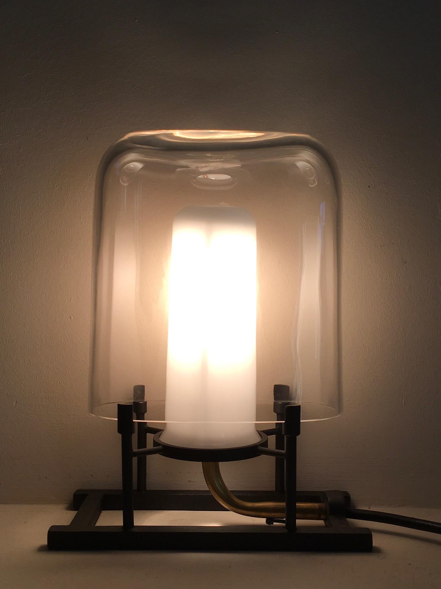 Lampe assez magique, l'ampoule halogène est recouverte par un tube de verre opalin et la commande du variateur est d'une grande précision.
Cette lampe a été conçue par Carlo Moretti et Paolo Marinuzzi en 1984, éditée par les frères Carlo et